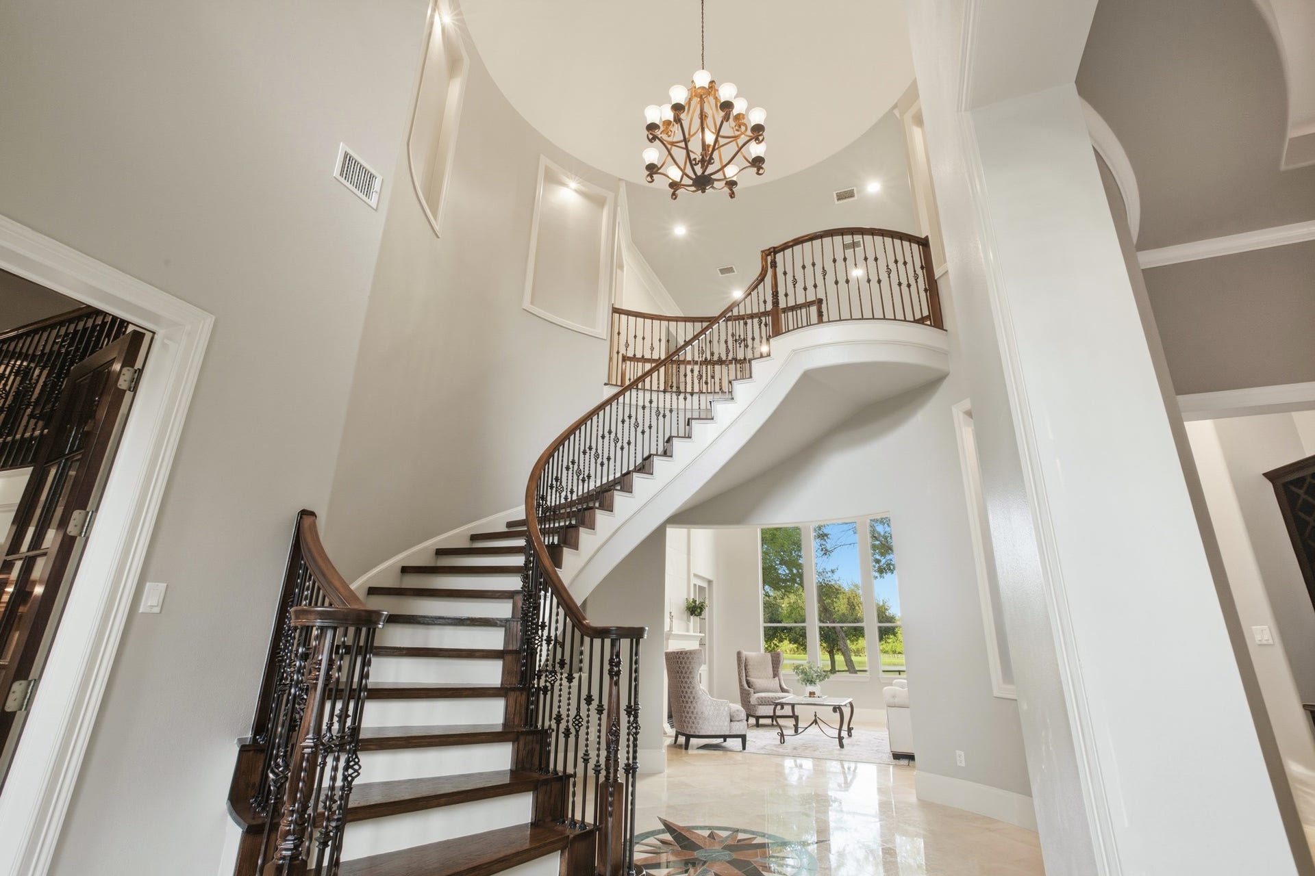 3518 River Forest Drive, Richmond, TX 77406 Grand foyer with a sweeping curved staircase, elegant chandelier, and abundant natural light, leading to a spacious living area.