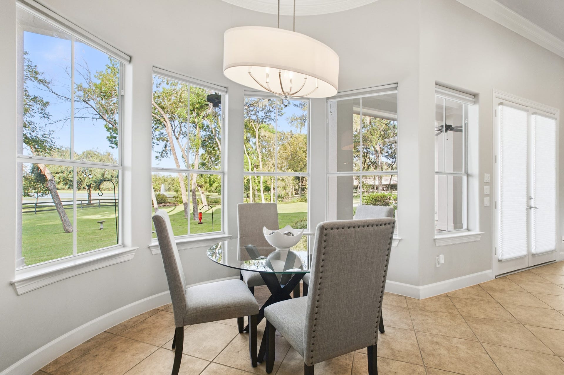 3518 River Forest Drive, Richmond, TX 77406 Bright breakfast nook with large windows offers stunning views of the lush backyard, enhanced by elegant tile flooring and a modern light fixture.