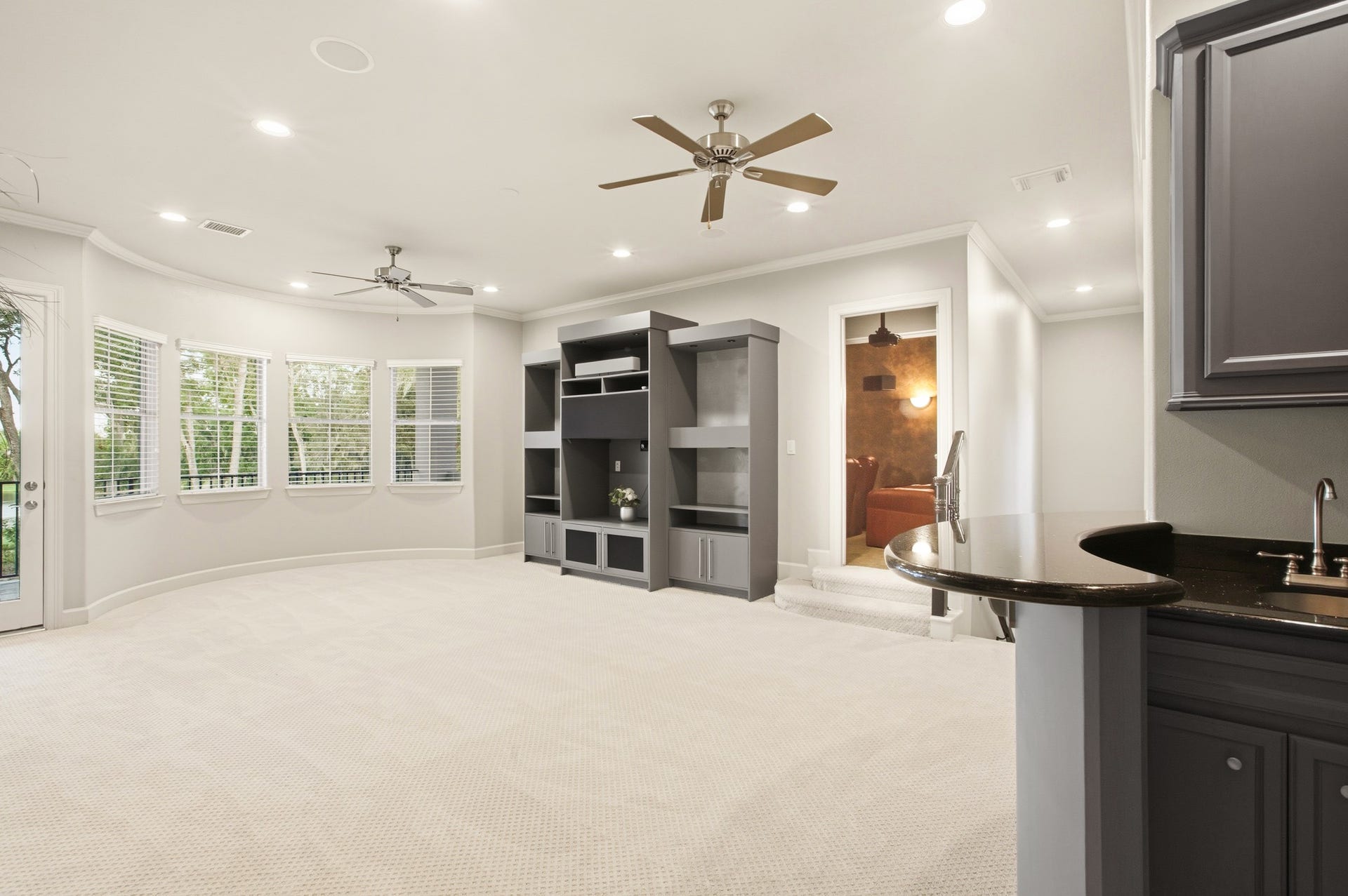 3518 River Forest Drive, Richmond, TX 77406 Step into a spacious game room perfect for entertainment, featuring sleek modern built-ins, a cozy alcove, and ample natural light streaming through large windows.