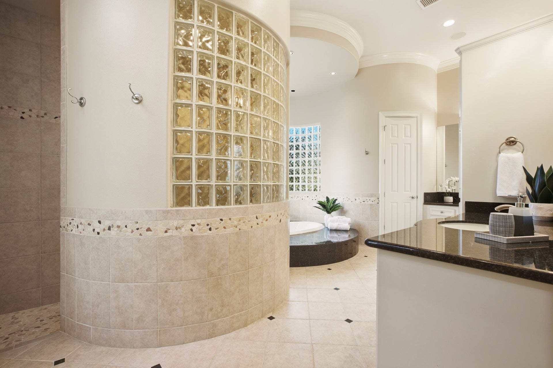 3518 River Forest Drive, Richmond, TX 77406 Luxurious bathroom featuring a spacious curved glass block shower, elegant tile work, and a sunken oval tub for ultimate relaxation.
