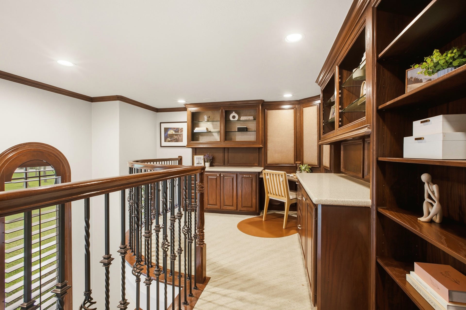 3518 River Forest Drive, Richmond, TX 77406 Charming mezzanite office space with rich wooden cabinetry, built-in shelves, and a cozy workspace overlooking elegant balustrades.