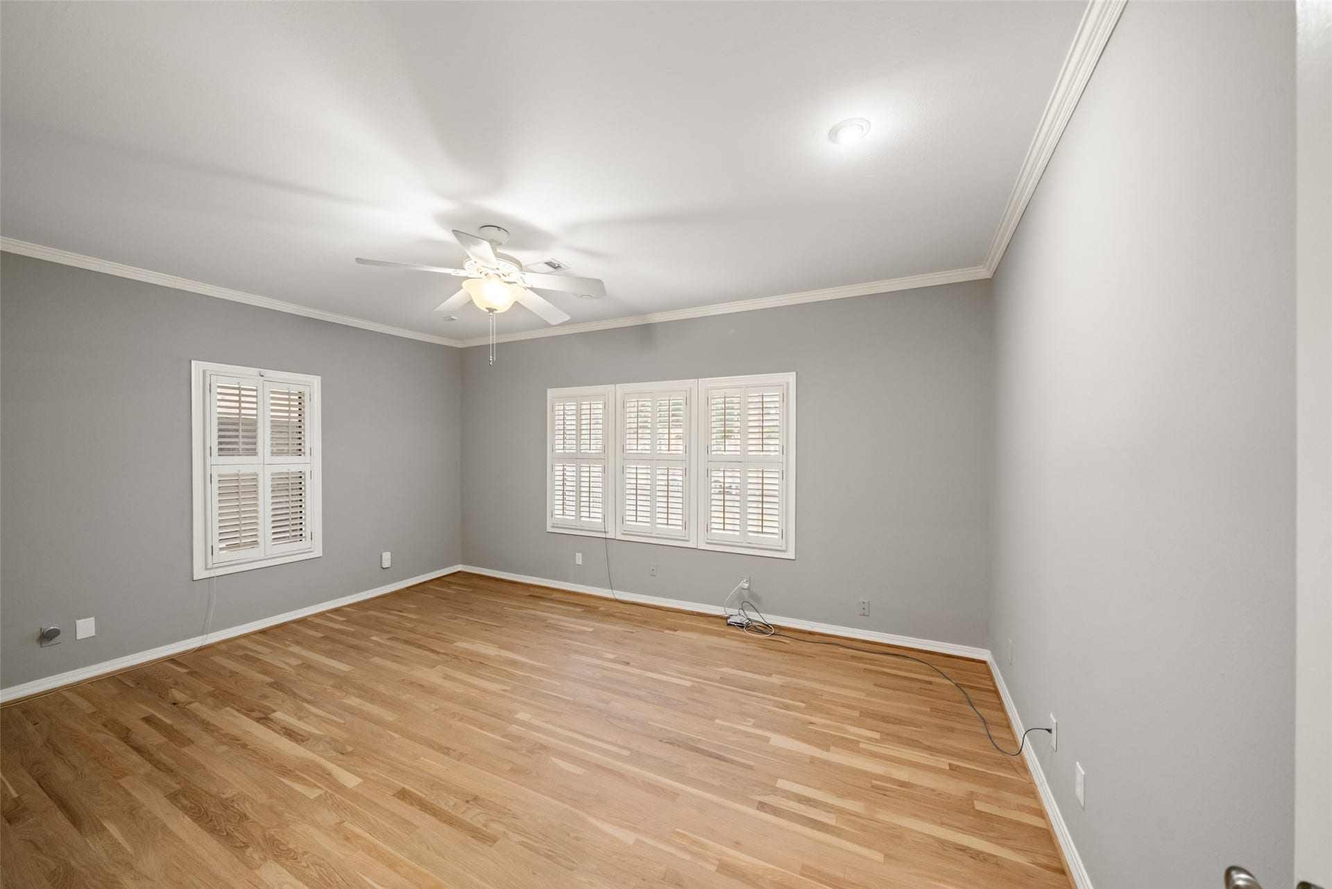 Front secondary bedroom with wood floors and window shutters, also suitable for use as a home office.