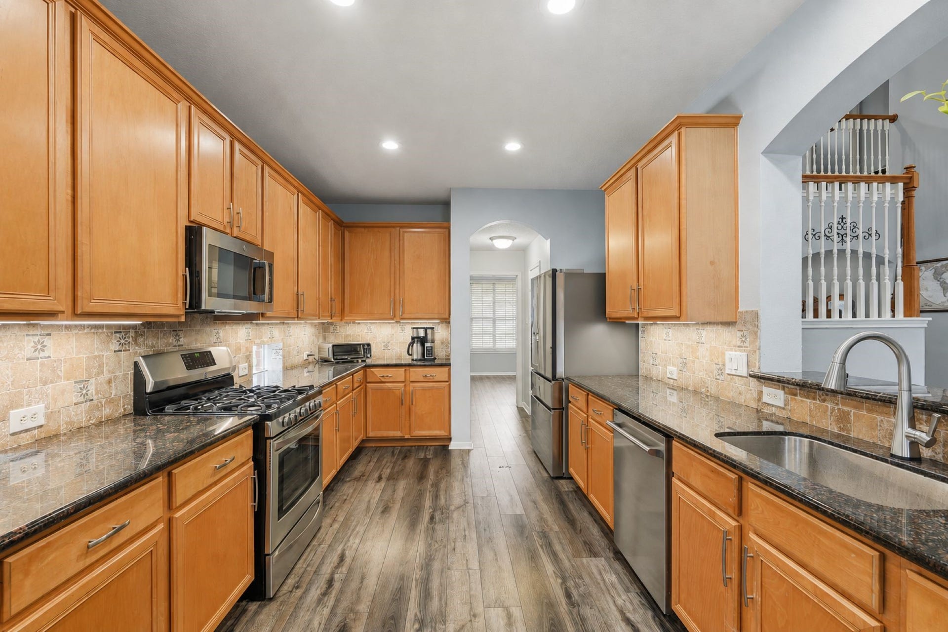 Updated kitchen with granite counters, modern backsplash, under counter lighting, and recessed lighting.