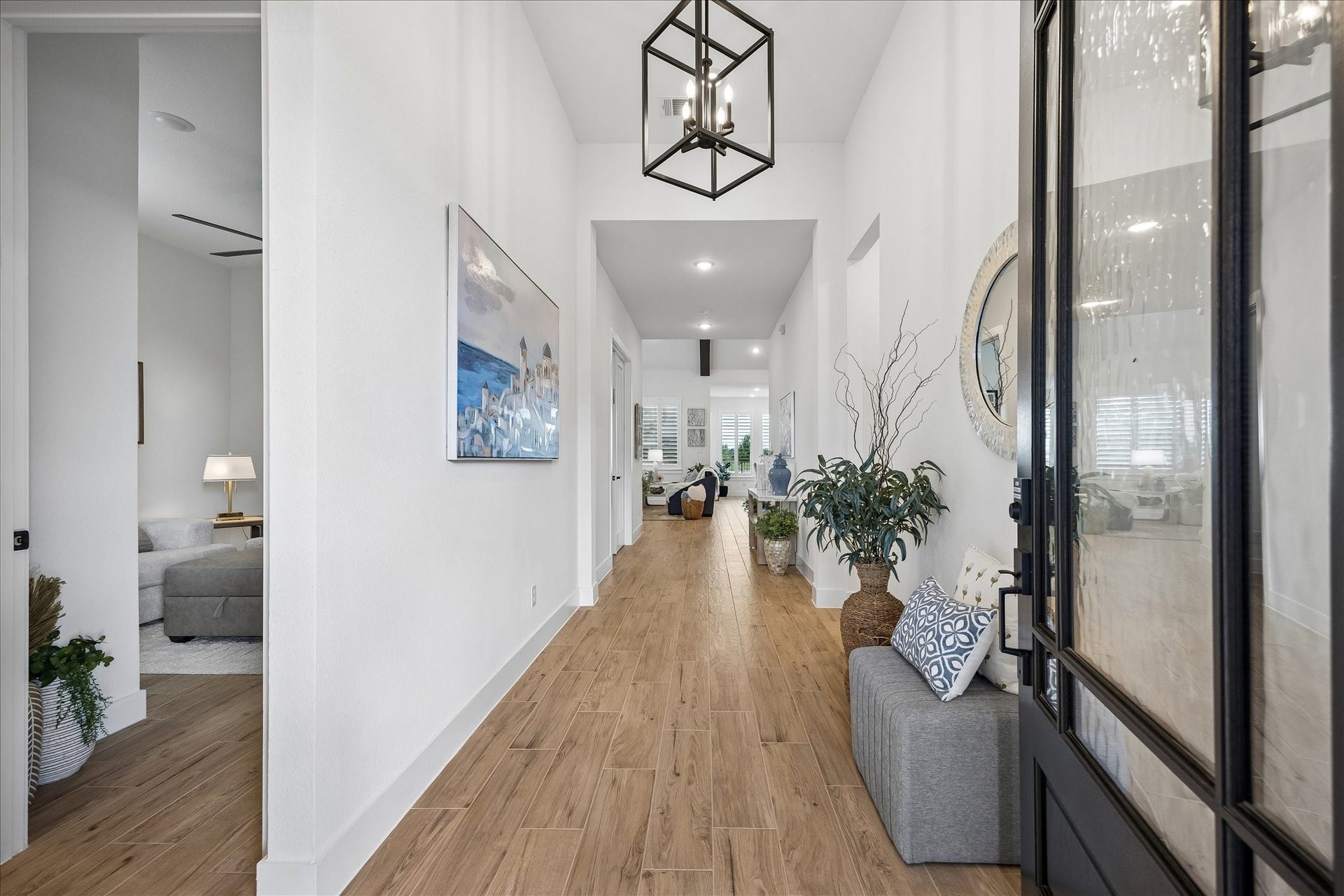 A welcoming, wide entry hallway showcases beautiful wood-plank tile flooring that flows seamlessly into the main living area and continues into the secondary bedroom, creating a warm and cohesive design throughout the home.