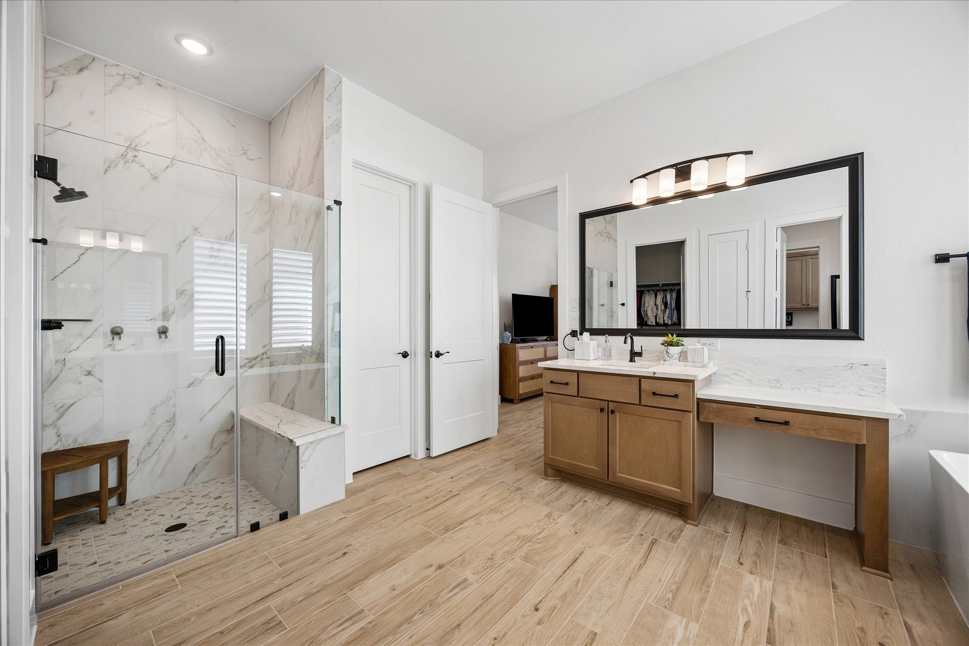 32438 Violet Dancer Court, Fulshear, TX 77441 The primary bathroom features a luxurious upgraded frameless glass shower with marble tile, modern matte black fixtures and a built-in bench. The suite also includes a private toilet room and spacious his-and-hers walk-in closets.