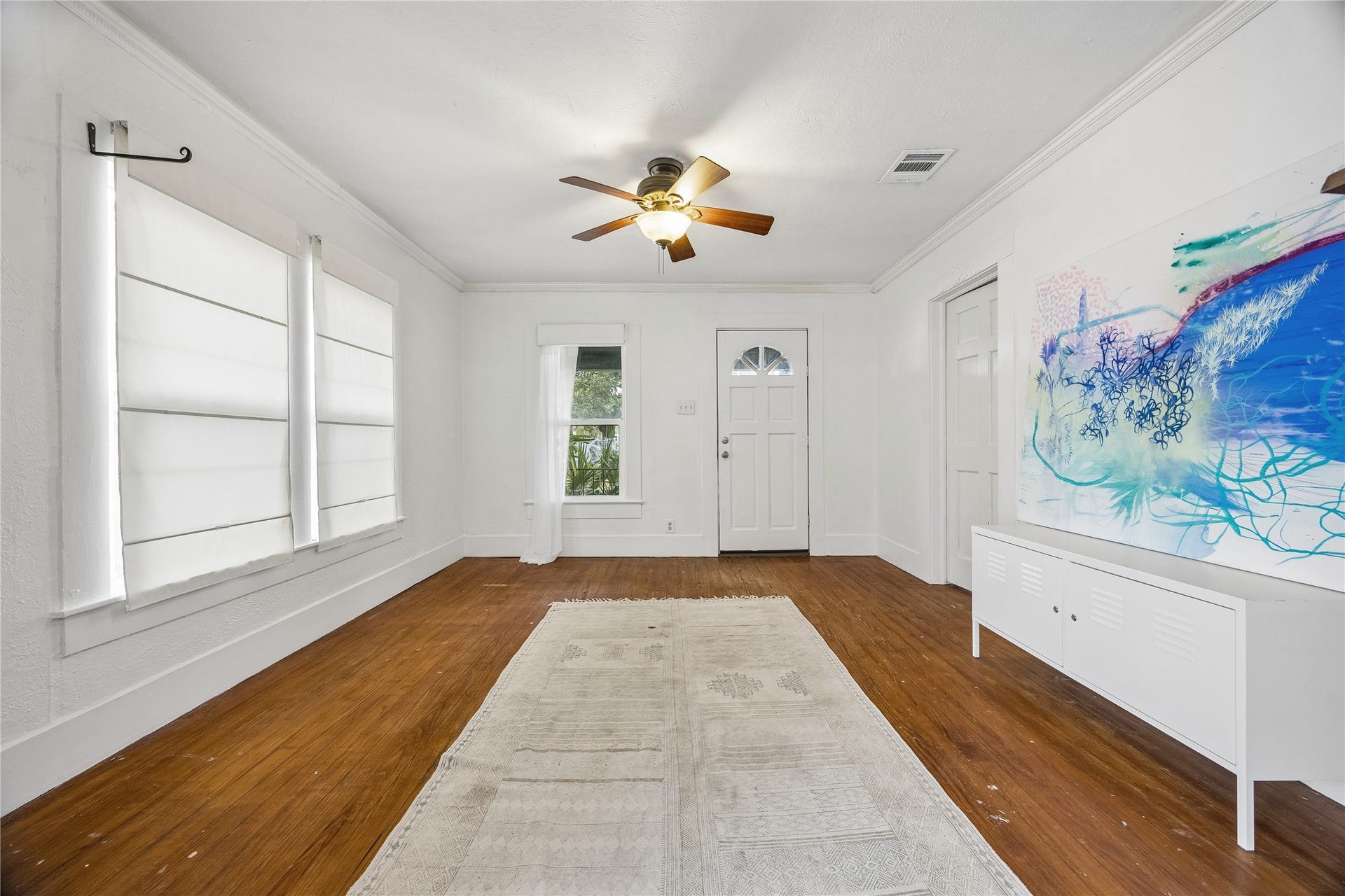 1039 Dunbar Street, Houston, TX 77009 Step inside to a bright, inviting living space featuring warm wood floors, crisp white walls, abundant windows, and a ceiling fan for added comfort
