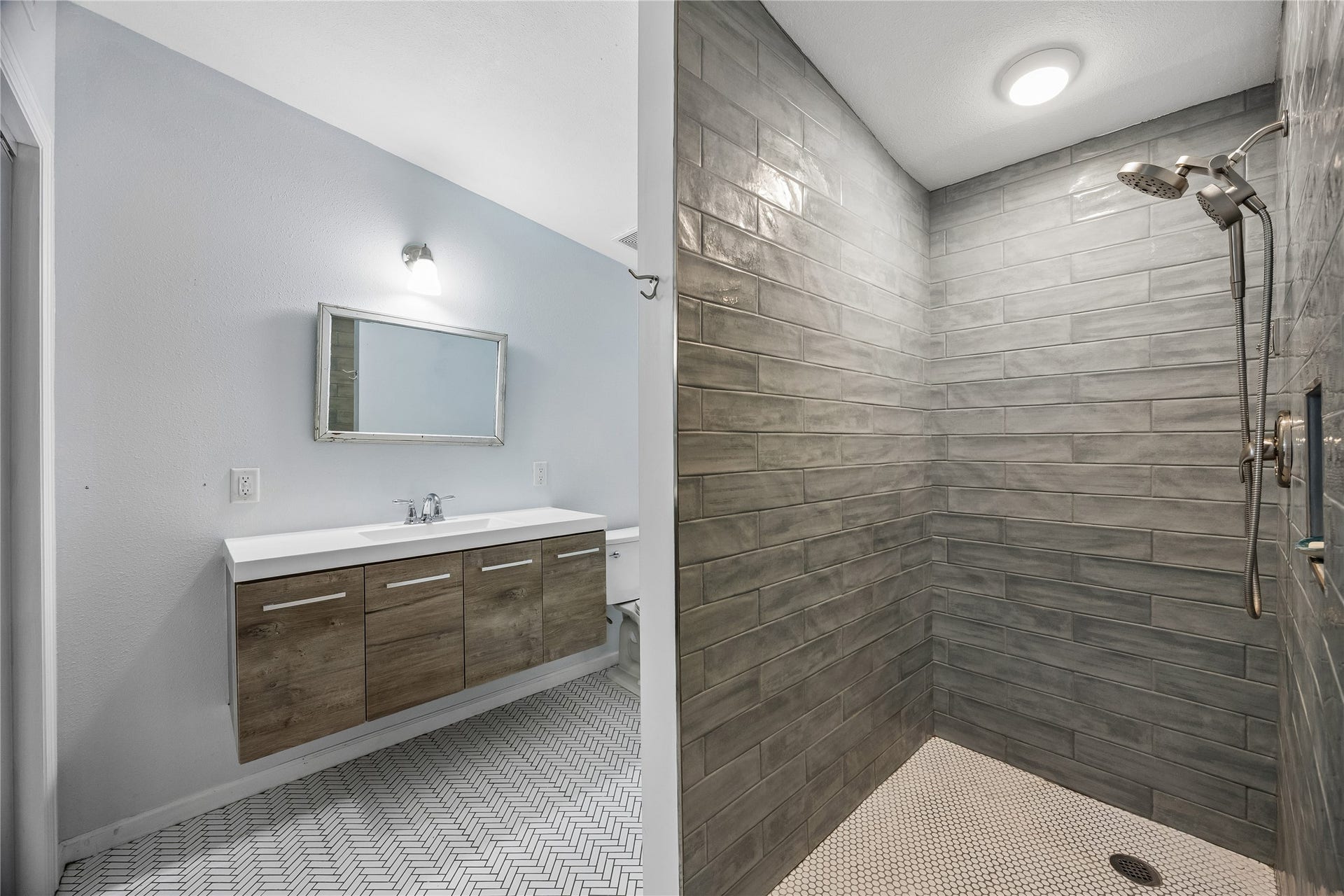 1039 Dunbar Street, Houston, TX 77009 This striking bath pairs a floating double vanity and patterned flooring with a spacious tiled walk-in shower for a clean, contemporary look