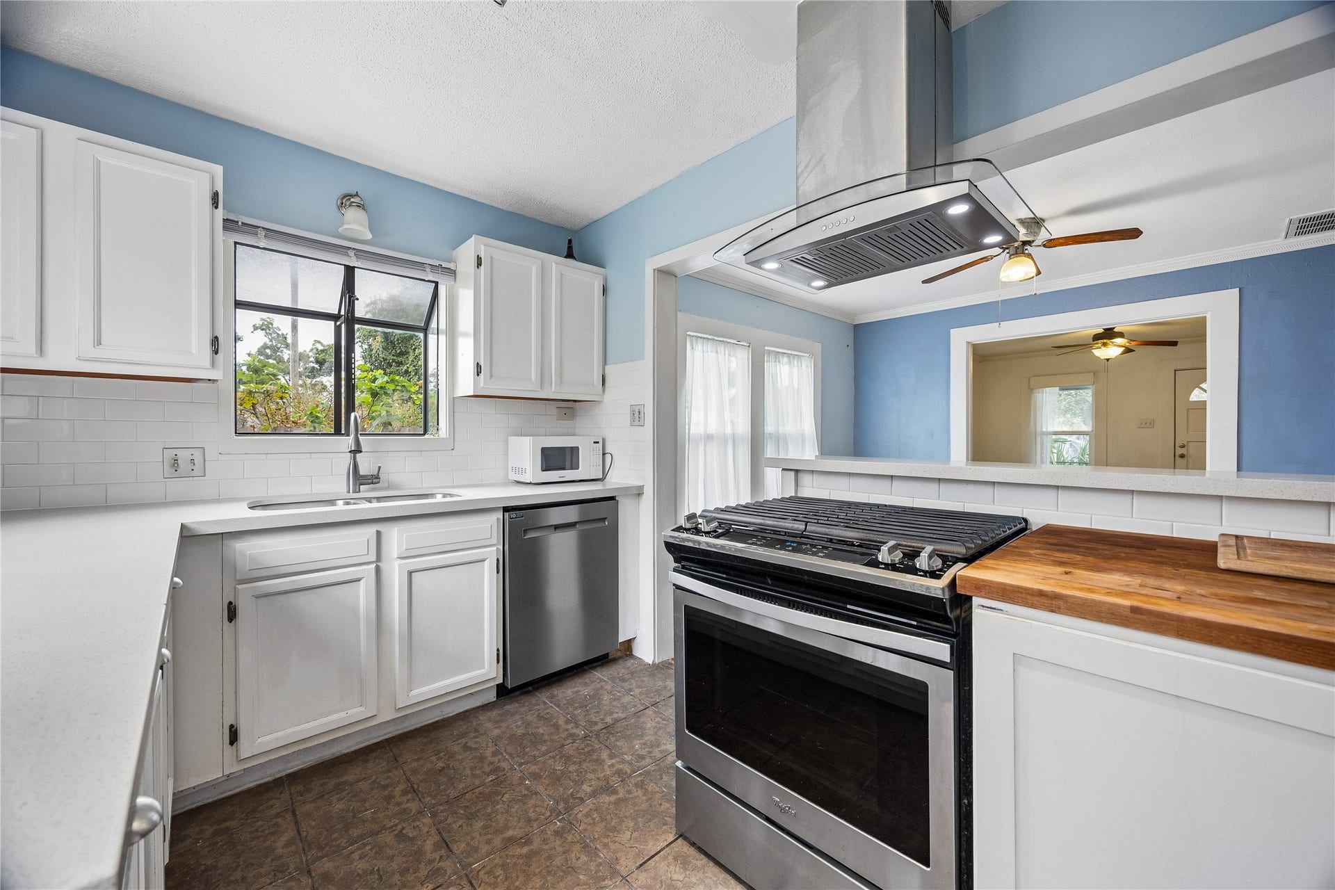 1039 Dunbar Street, Houston, TX 77009 Another view of the kitchen showcases its cheerful blue-and-white palette, stainless-steel appliances, butcher-block counter accent, and convenient opening to the adjoining room.