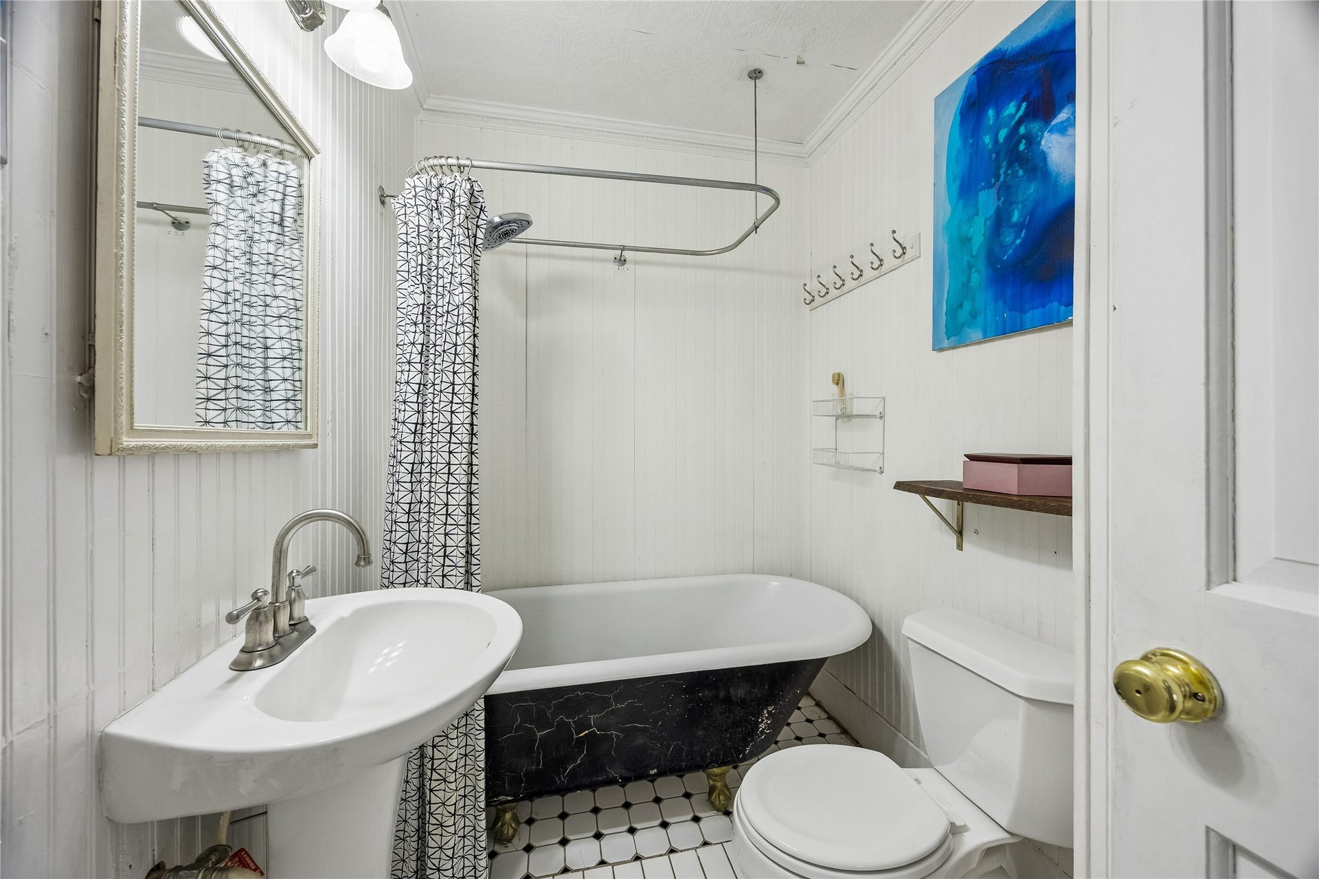 1039 Dunbar Street, Houston, TX 77009 Vintage character shines in this bath, where a classic clawfoot-style tub, pedestal sink, paneled walls, and patterned tile floor create a delightfully distinctive space.