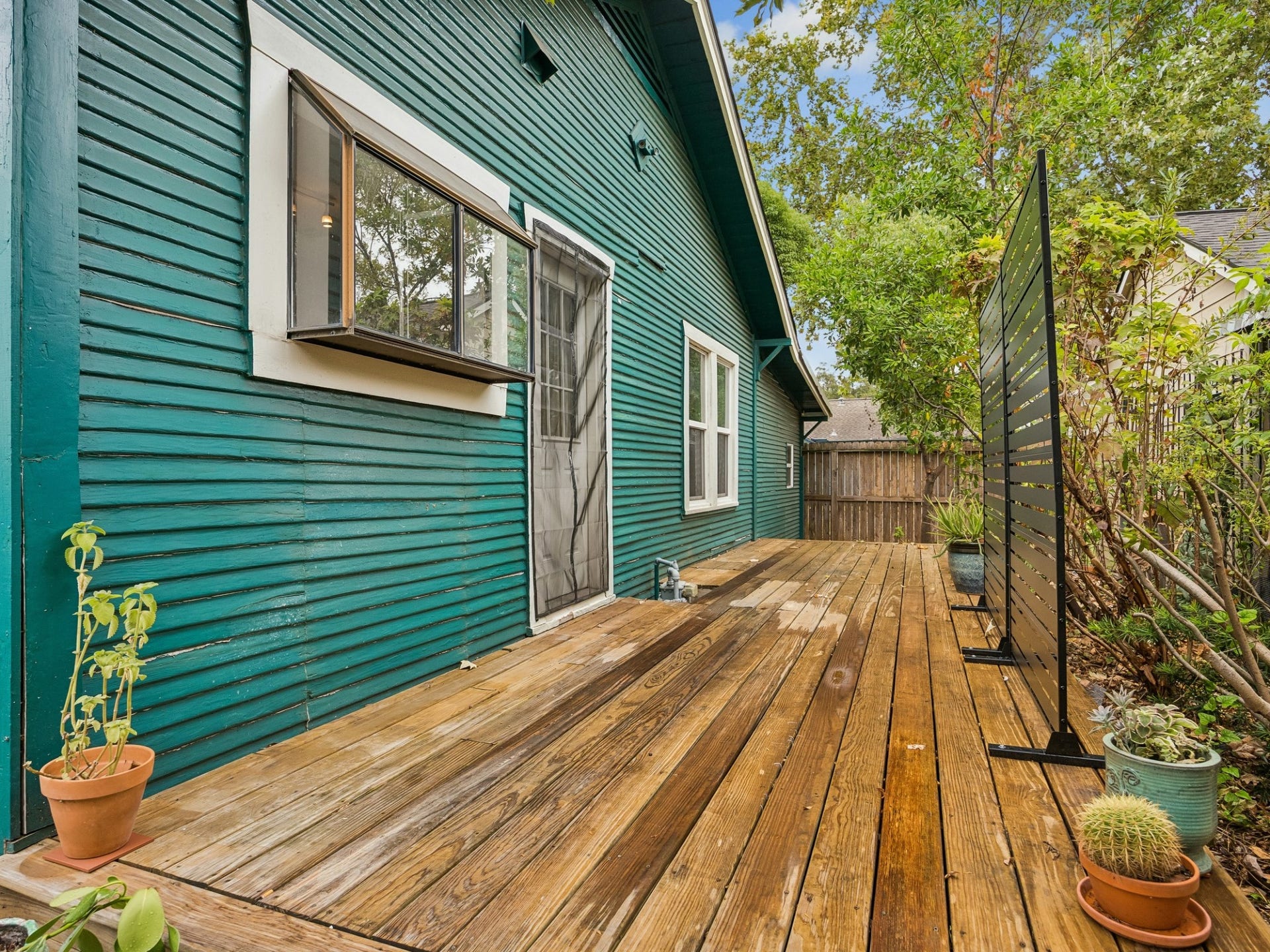 1039 Dunbar Street, Houston, TX 77009 Step outside to a private-feeling wooden deck surrounded by greenery, offering an inviting spot for morning coffee, container gardening, or relaxed outdoor lounging