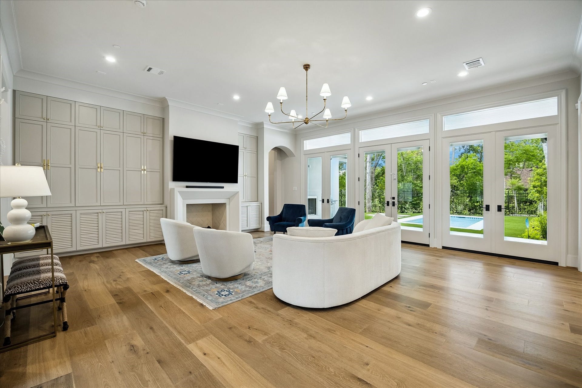 10801 Long Shadow Lane, Hunters Creek Village, TX 77024 The living room unfolds with refined elegance, showcasing French white oak wide plank hardwood flooring, soaring 11-foot ceilings, custom trim and crown molding. A wood-burning fireplace with surrounding built-ins anchors the space, while a wall of French doors frames serene views of the backyard and fills the room with natural light.