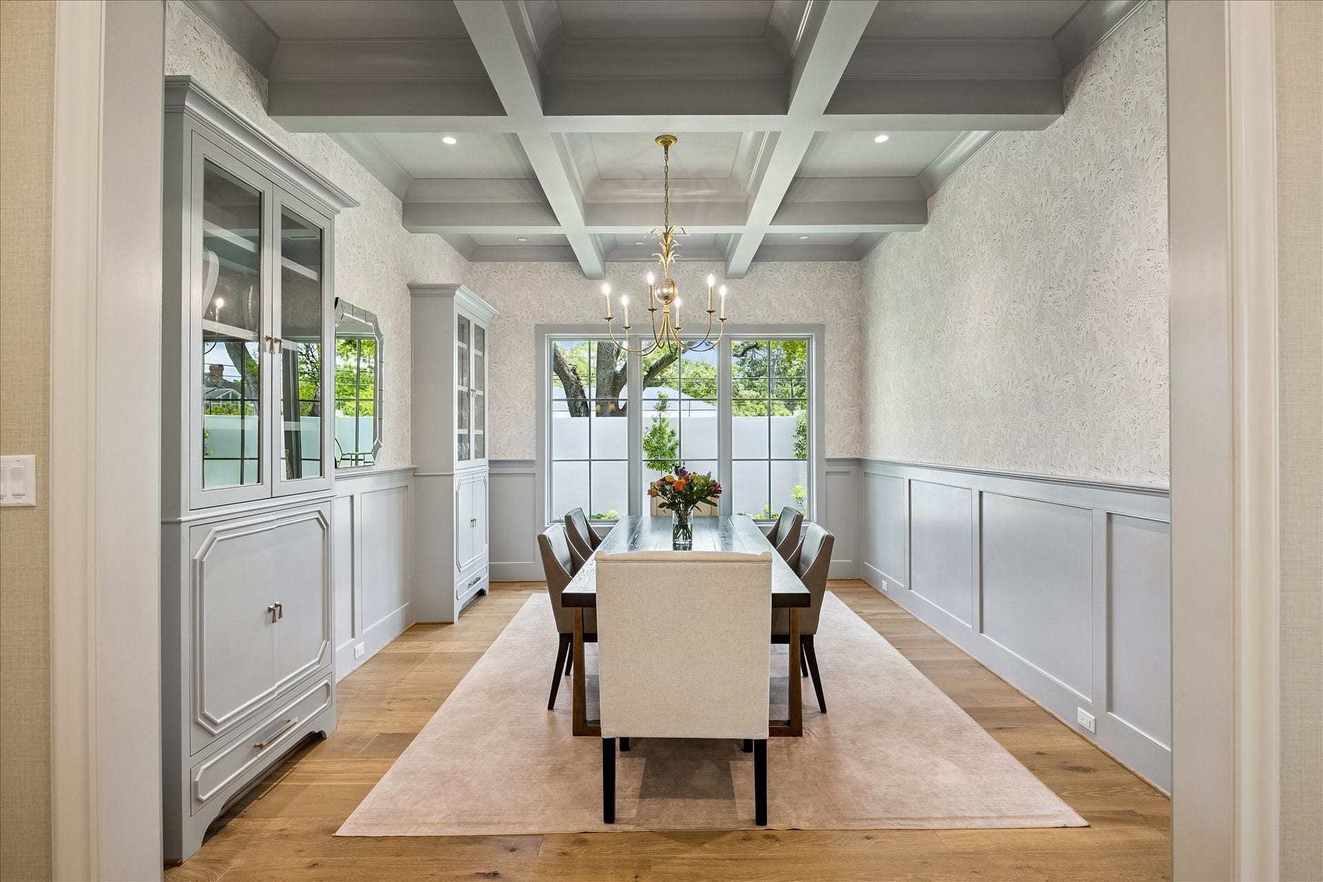 10801 Long Shadow Lane, Hunters Creek Village, TX 77024 Formal dining room featuring a striking coffered ceiling, classic candelabra-style chandelier, gorgeous wallpaper and wainscotting. Fantastic custom built-in cabinetry and large windows create a bright, sophisticated setting for dining and entertaining.
