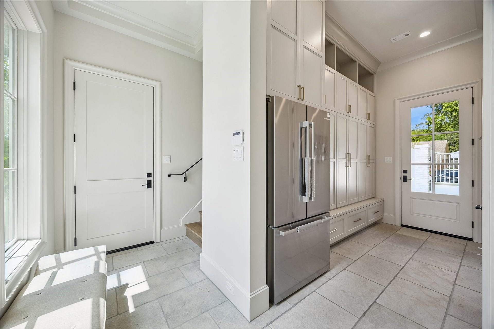 10801 Long Shadow Lane, Hunters Creek Village, TX 77024 Spacious, well-appointed mudroom featuring tumbled limestone flooring and wall of custom built-in cabinetry for added storage and functionality. Includes a stainless refrigerator/freezer, a conveniently located half bath, and a staircase leading to the spacious mother-in-law or guest suite!