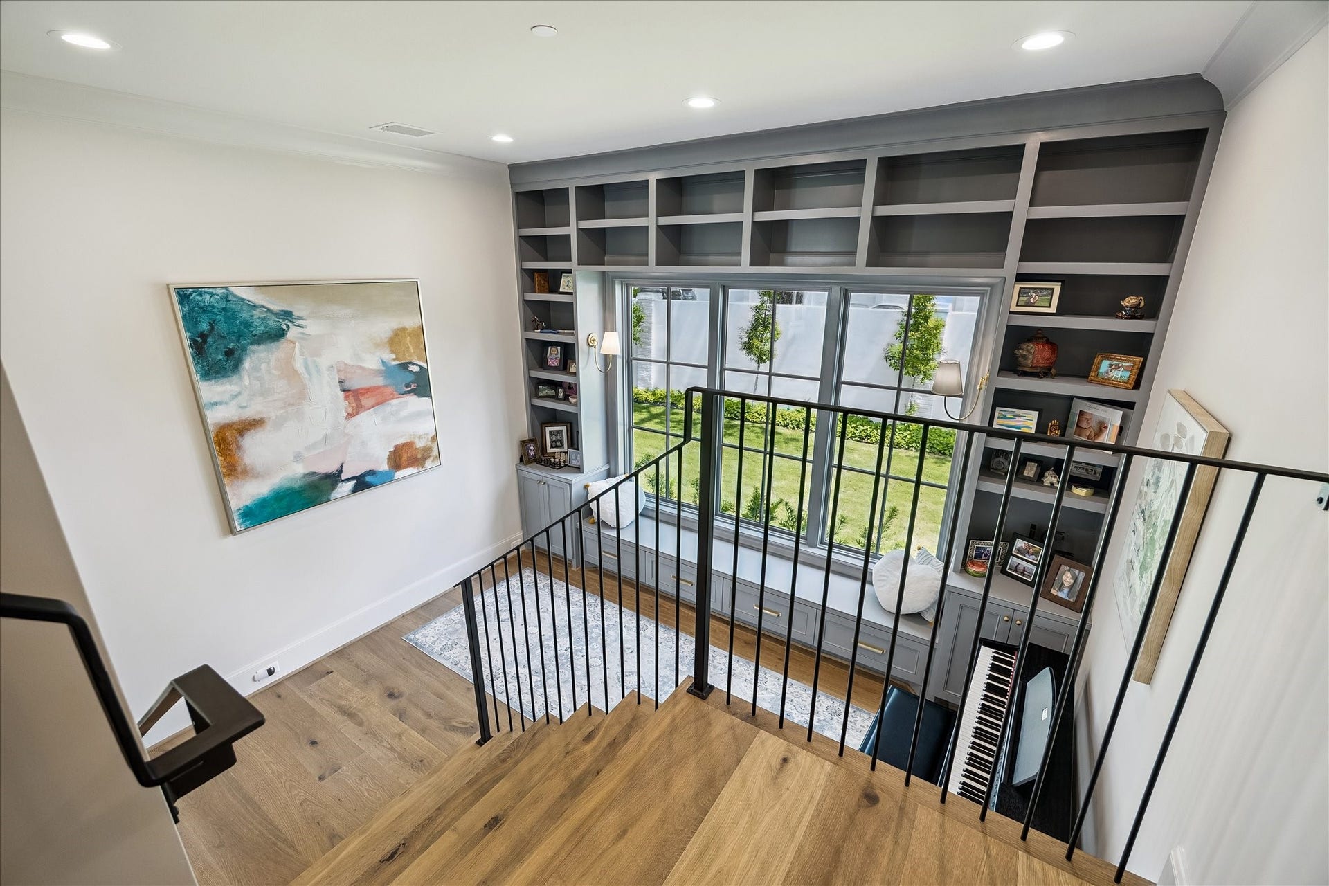 10801 Long Shadow Lane, Hunters Creek Village, TX 77024 Overlooking the flex space below, the upper landing showcases the homes open design and impressive scale. Custom built-ins extend to the upper level, adding architectural interest and display space, while the large divided light window fills the area with natural light and views of the side yard and beautiful landscaped grounds. We love the view of the privacy wall and landscaping outdoors.
