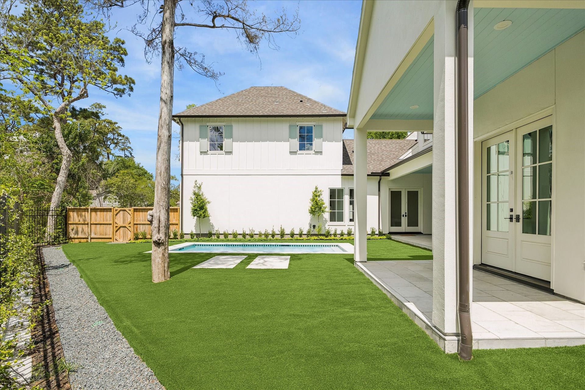 10801 Long Shadow Lane, Hunters Creek Village, TX 77024 Additional green space with expansive turf surrounding the pool, offering flexible room for outdoor activities and relaxation. This covered patio overlooks the backyard while fencing maintains privacy along the wooded ravine perimeter.