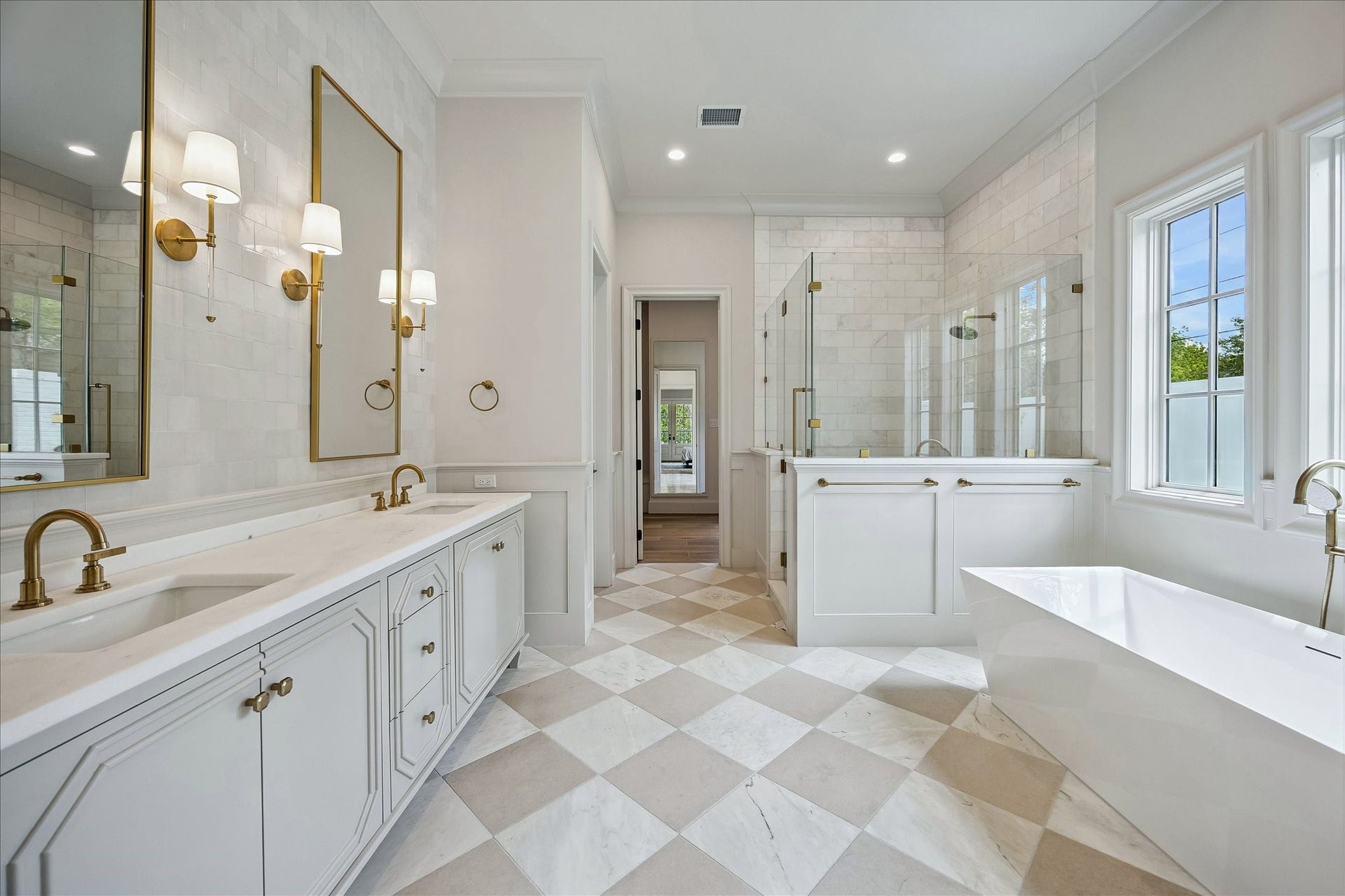 10801 Long Shadow Lane, Hunters Creek Village, TX 77024 The luxurious primary bath reveals a beautifully designed dual vanity with custom designed cabinetry, marble countertops, and designer sconces flanking the beautiful, framed mirrors. The marble and limestone 18x18 checkerboard flooring continues throughout, complementing the sophisticated palette, while thoughtful details and high-end finishes create a cohesive and luxurious primary suite bath.