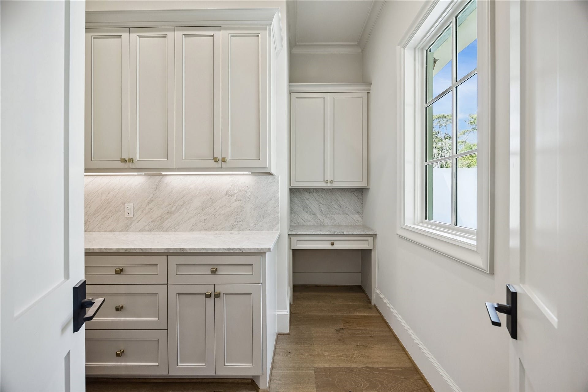 10801 Long Shadow Lane, Hunters Creek Village, TX 77024 Expansive walk-in pantry featuring marble slab backsplash, custom cabinetry with soft-close drawers and doors, and under-cabinet lighting. Built-in workstation adds functionality, creating a refined and highly organized prep space.