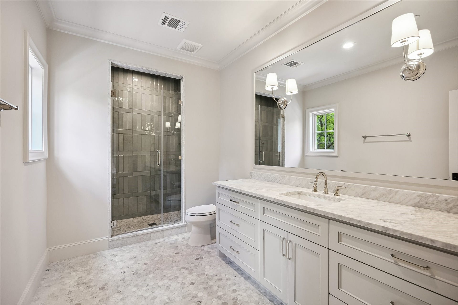 10801 Long Shadow Lane, Hunters Creek Village, TX 77024 Well-appointed ensuite bath featuring mosaic Carrara tile flooring, marble slab counters, custom cabinetry, and a spacious frameless glass-enclosed shower with gorgeous contrasting tile to the ceiling that adds visual interest. Clean, classic finishes create a bright and functional space. The window in this bathroom adds wonderful natural light!!!