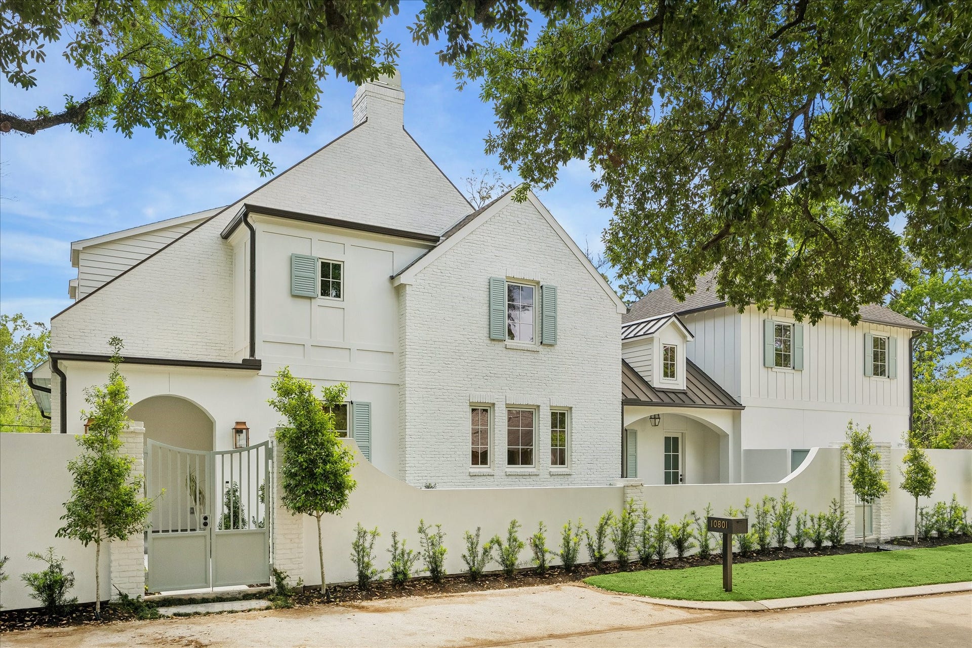 10801 Long Shadow Lane, Hunters Creek Village, TX 77024 Exterior with gated courtyard entry, ravine location with manicured landscaping, mature trees, turf and pool creating a private, estate-style setting. Timeless architecture highlighted by shutters, arched openings & refined exterior finishes. We love this extra parking space that was created in the front of the home!