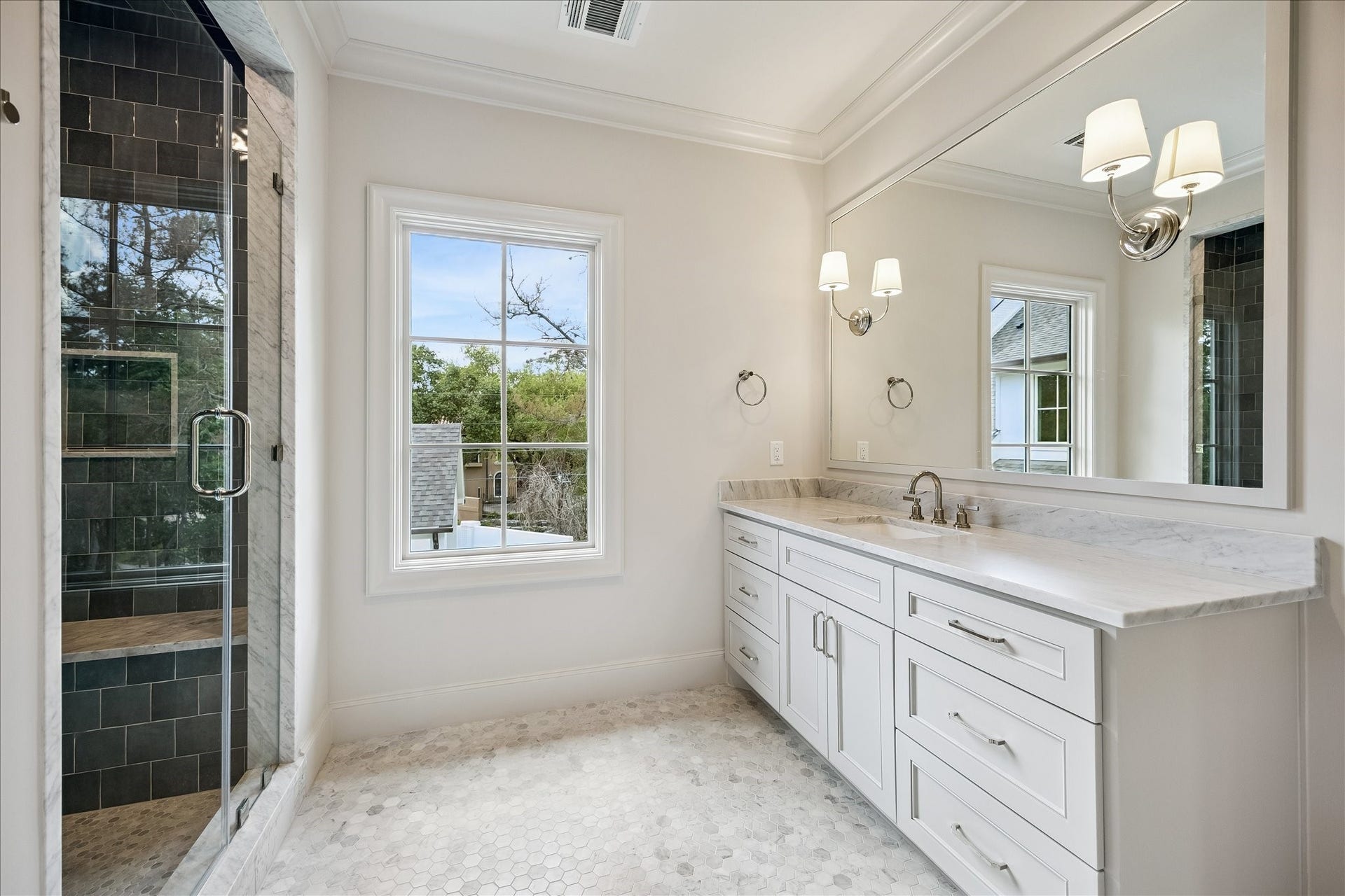 10801 Long Shadow Lane, Hunters Creek Village, TX 77024 Well-appointed full bath in the mother-in-law/guest suite featuring a marble slab countertop and backsplash, custom vanity with polished hardware, and a framed mirror with sconce lighting. A frameless glass-enclosed shower with beautiful tile surround to the ceiling adds a refined, spa-like touch.