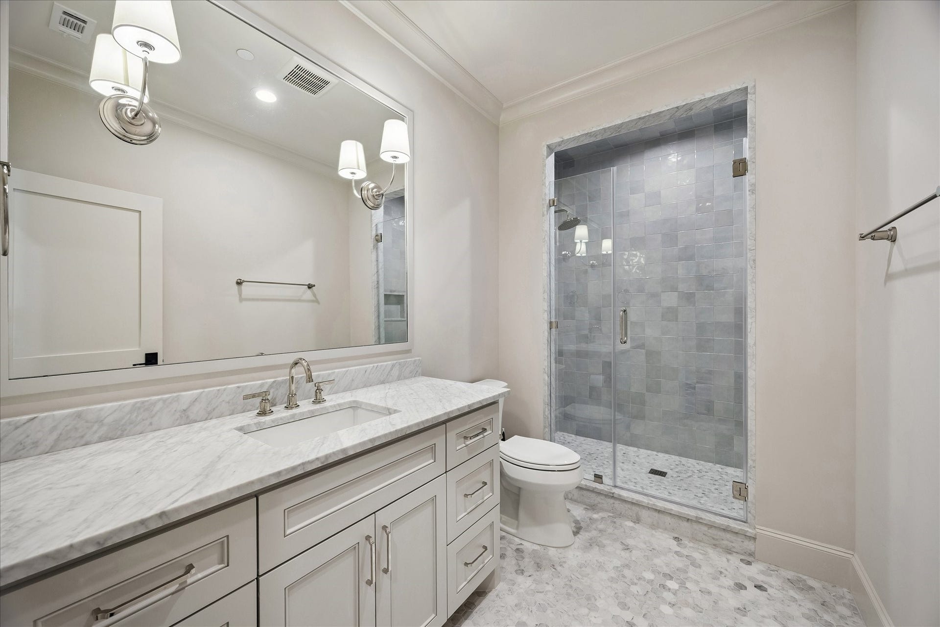 10801 Long Shadow Lane, Hunters Creek Village, TX 77024 Beautifully appointed ensuite bath featuring Carrara mosaic tile flooring, marble slab counter, custom cabinetry, and a frameless glass-enclosed shower with striking contrasting tile to the ceiling for added visual interest. Clean, classic finishes create a bright and inviting space.