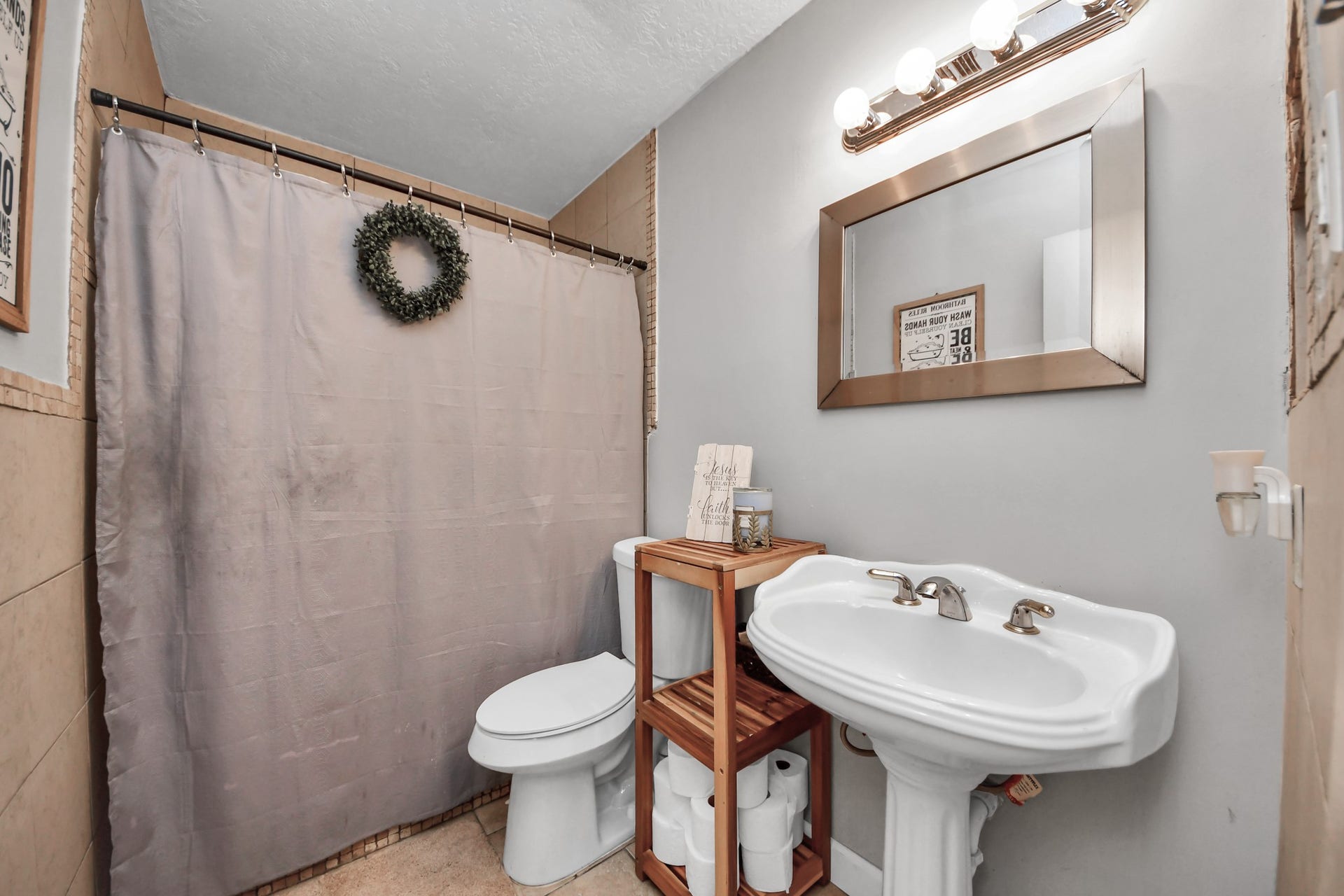 Spacious secondary bathroom featuring a tiled walk-in shower, pedestal sink, and a neutral color palette. A functional layout with charming details and room for everyday convenience.
