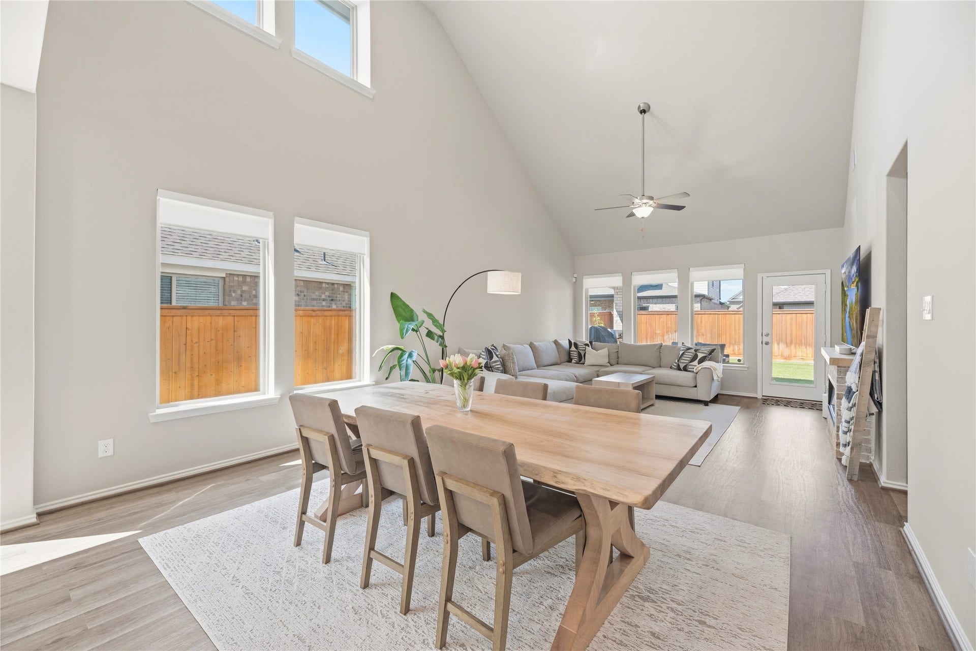 The dining area features a two-story wall of windows providing abundant natural light.