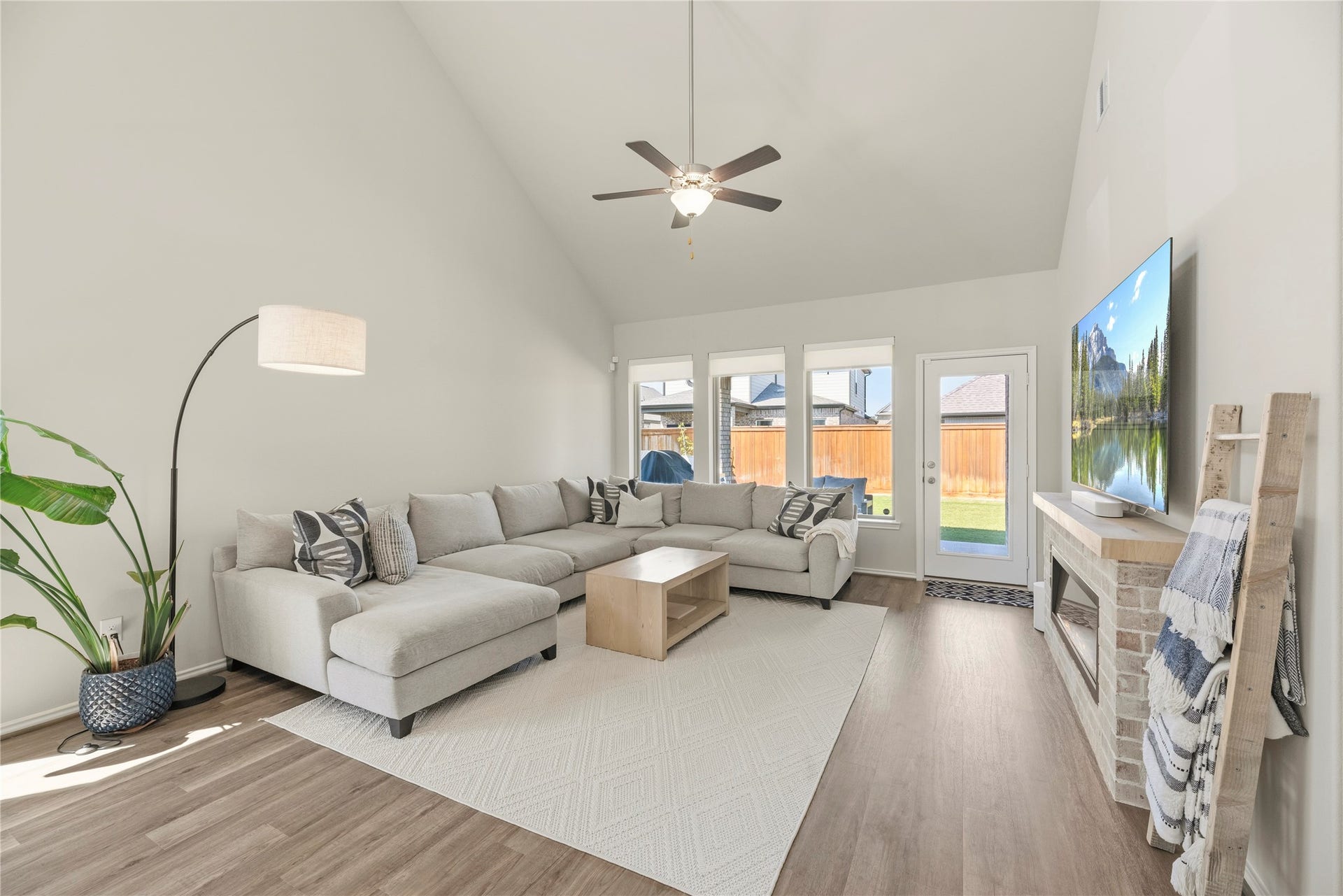 This bright and airy living room features high ceilings, a cozy fireplace, and windows overlooking the covered patio and backyard.