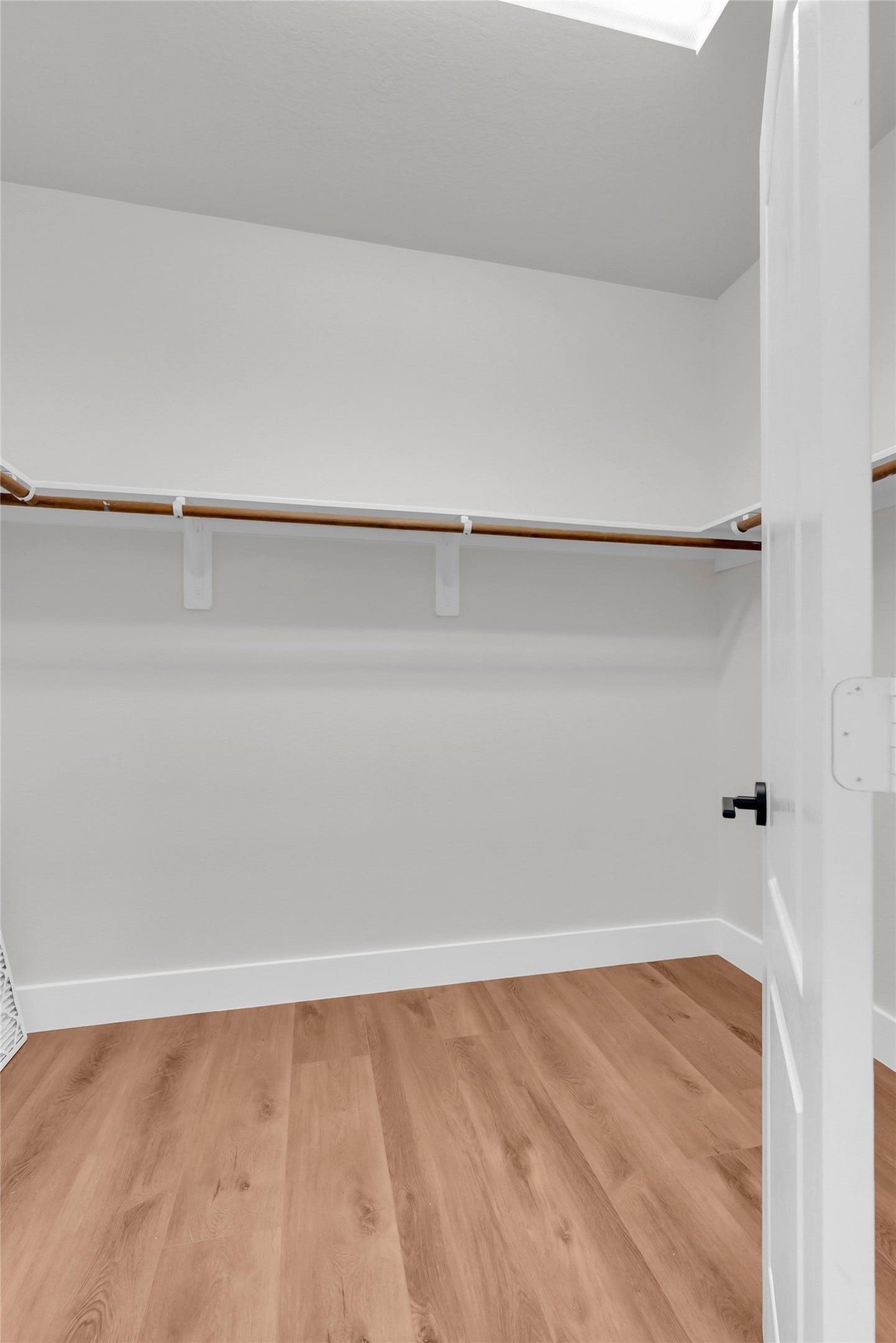78 Heritage Mill, The Woodlands, TX 77375 Primary walk-in closet featuring built-in shelving, ample hanging space, and gorgeous new wood flooring, offering practical storage and organization.