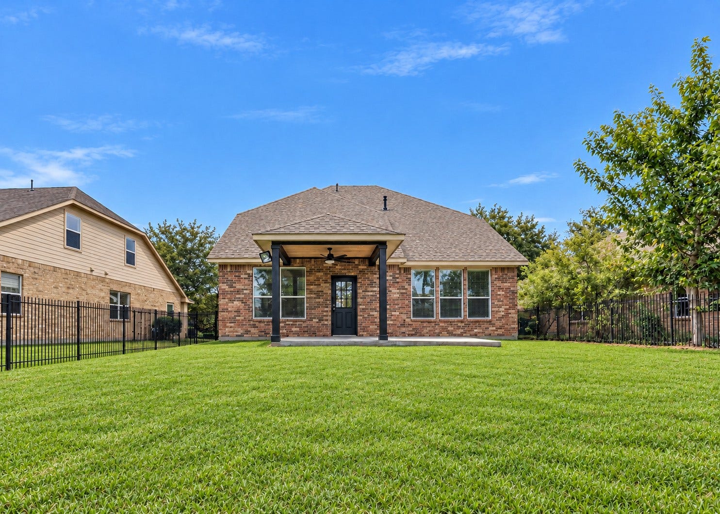 78 Heritage Mill, The Woodlands, TX 77375 Expansive, fully fenced backyard with lush green lawn, mature trees, and a covered patio, offering plenty of space for outdoor entertaining, recreation, and relaxation.