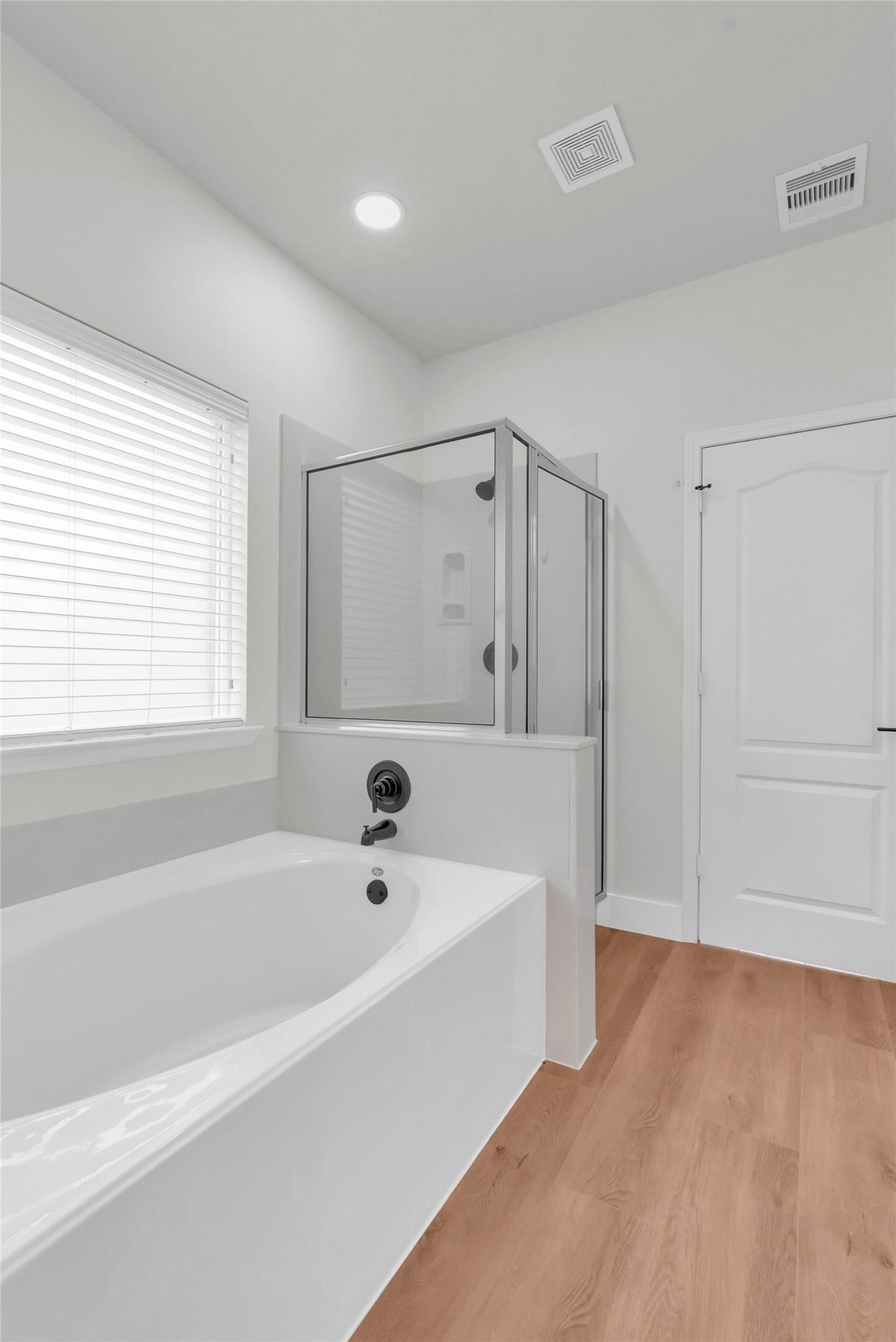 78 Heritage Mill, The Woodlands, TX 77375 Light-filled primary bathroom featuring a relaxing soaking tub, separate walk-in shower, modern finishes, and beautiful natural light for a serene, spa-like atmosphere.