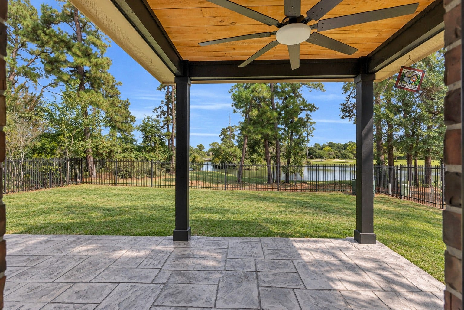 78 Heritage Mill, The Woodlands, TX 77375 Enjoy peaceful waterfront views from the spacious covered patio, featuring a beautiful wood-paneled ceiling and a serene backdrop of Schweinle Lake and towering trees.