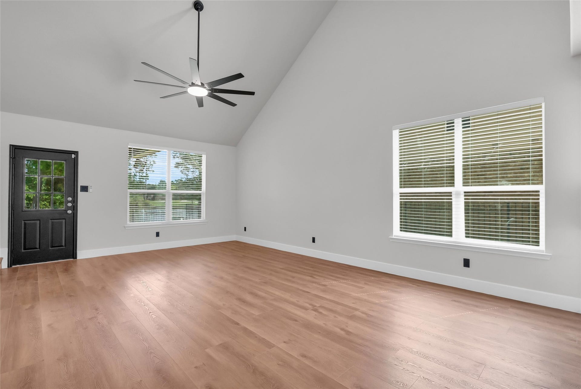78 Heritage Mill, The Woodlands, TX 77375 Inviting living room featuring soaring ceilings, gorgeous new wood flooring, and large windows that fill the space with natural light and showcase peaceful outdoor views.