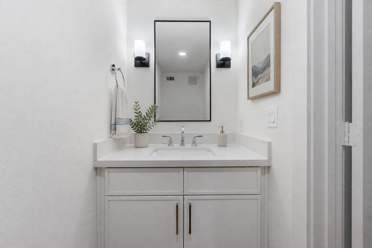Tucked Away  The powder room is designed to ensure privacy while being conveniently
accessible. Painted vanity, quartz countertop, undermount porcelain sink, wall mounted faucet,
framed mirror flanked by elegant light sconces on both sides.