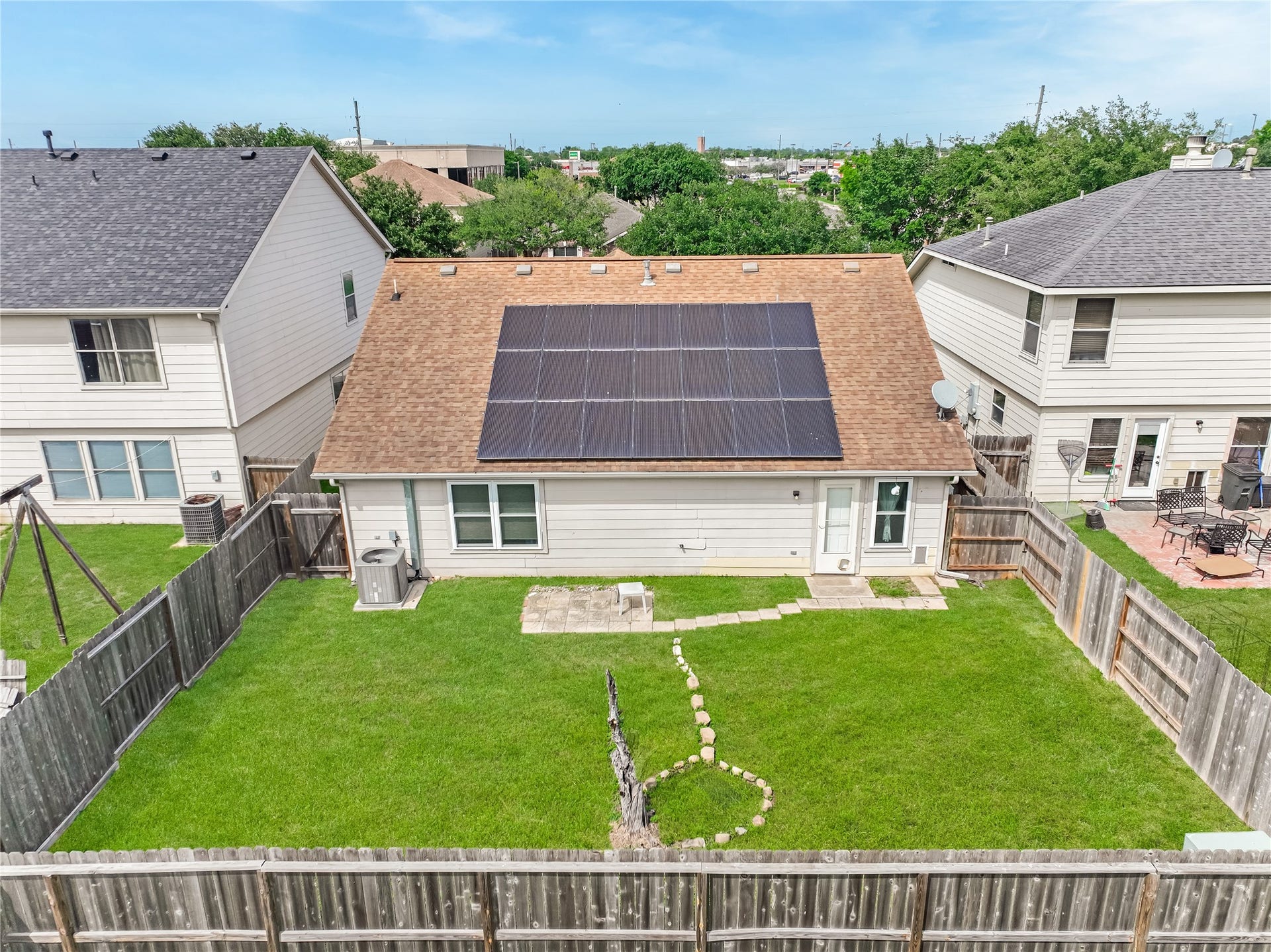 20911 Harvest Terrace Lane, Spring, TX 77379 Rear exterior view of the house featuring a spacious backyard, landscaped lawn, & solar panels.