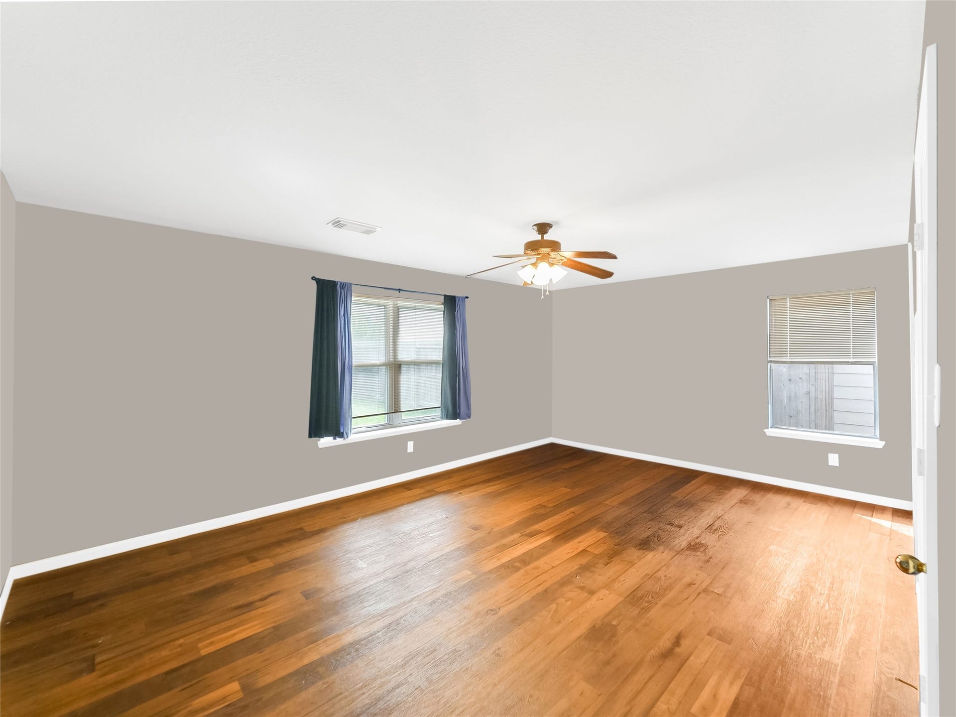 20911 Harvest Terrace Lane, Spring, TX 77379 Spacious primary bedroom with wood flooring, windows, and a ceiling fan.