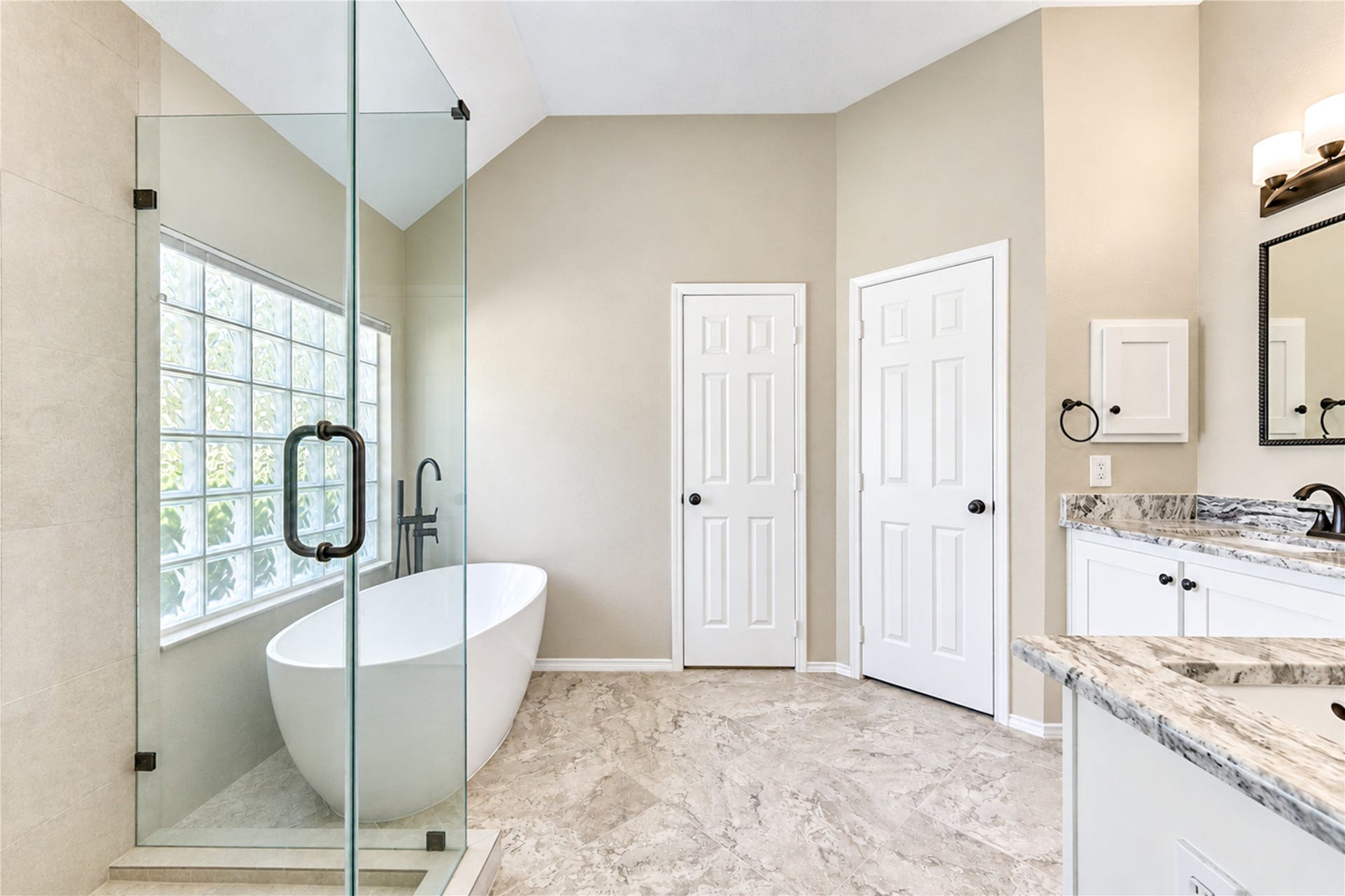 A relaxing space to retreat when you need a break.  This bathroom was thoughtfully updated with a soaker tub and separate shower, dual sinks, and ample storage.  Storing clothes won't be a problem with the large walk-in closet behind one of those doors.