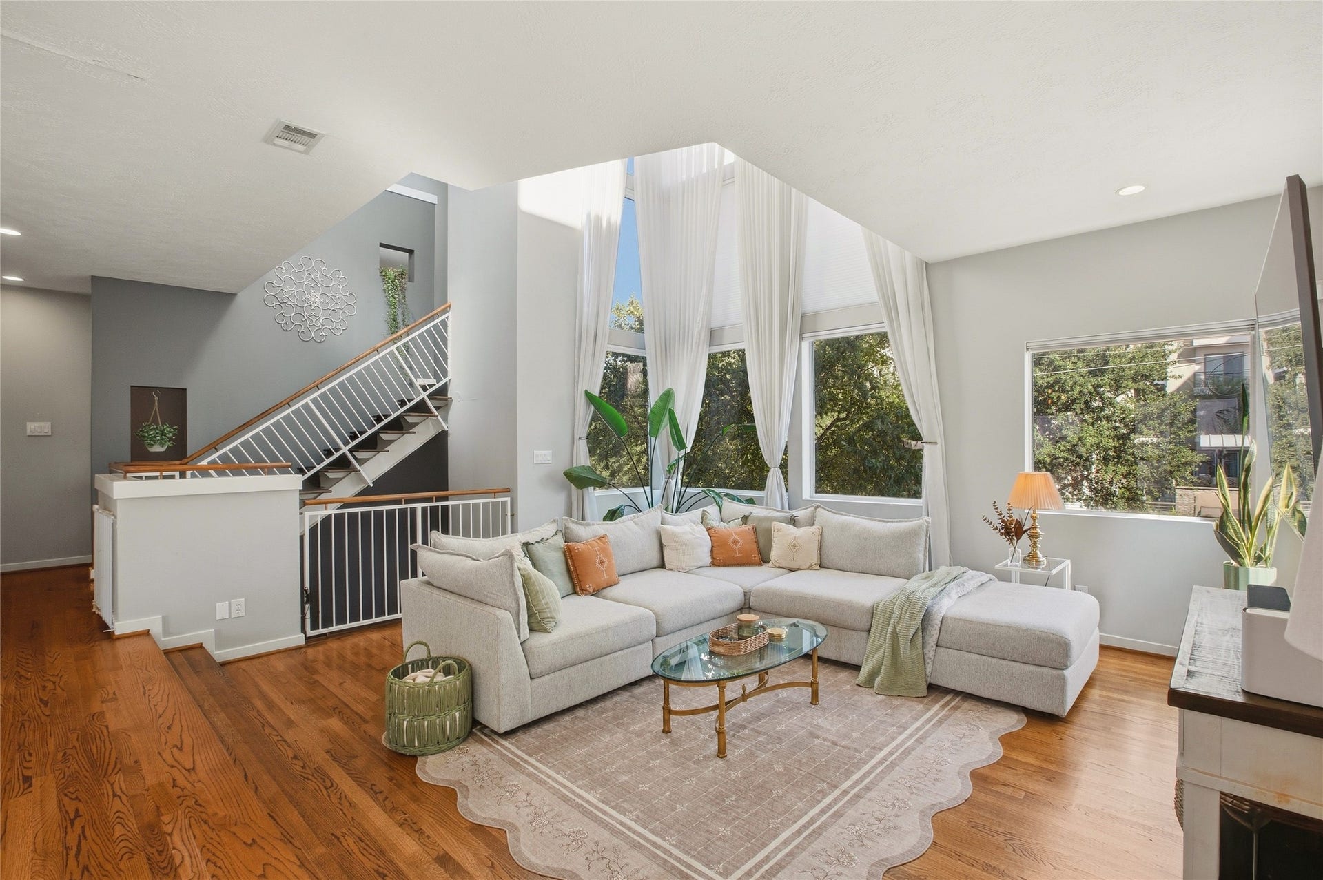 1803 Oneil Street, #C, Houston, TX 77019 Light-filled living room framed by treetop views and floor-to-ceiling drapes.