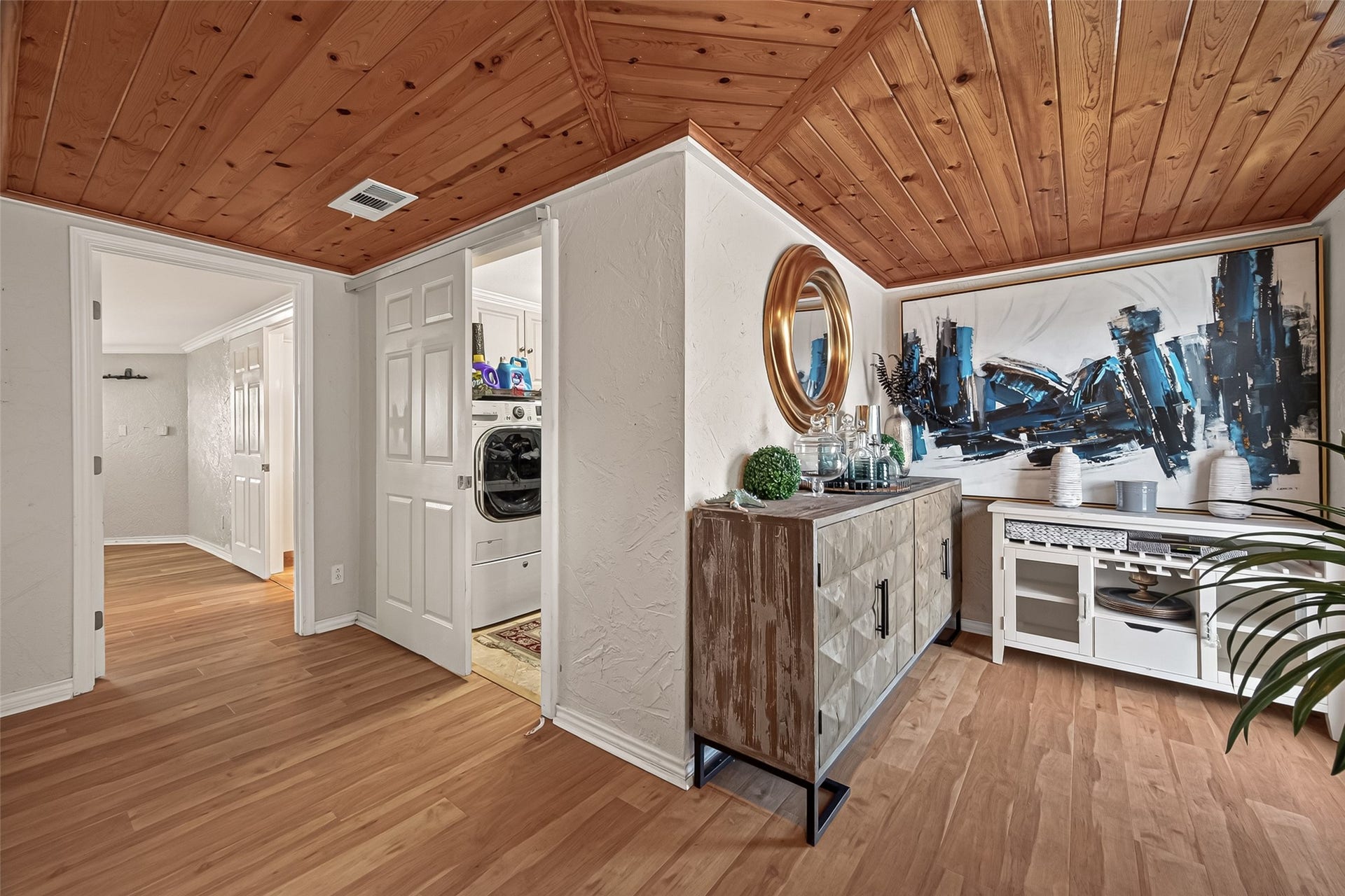 The interior showcases brilliant natural light, crisp white wall tones, striking wood-planked ceilings, and cohesive wood-tone flooring.