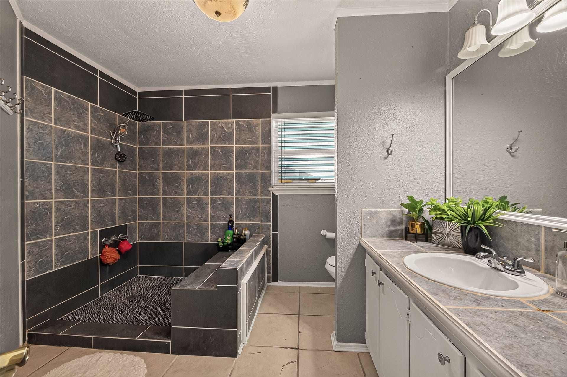 An impressive, open-concept shower hall clad in custom tile work and finished with an integrated seating bench.