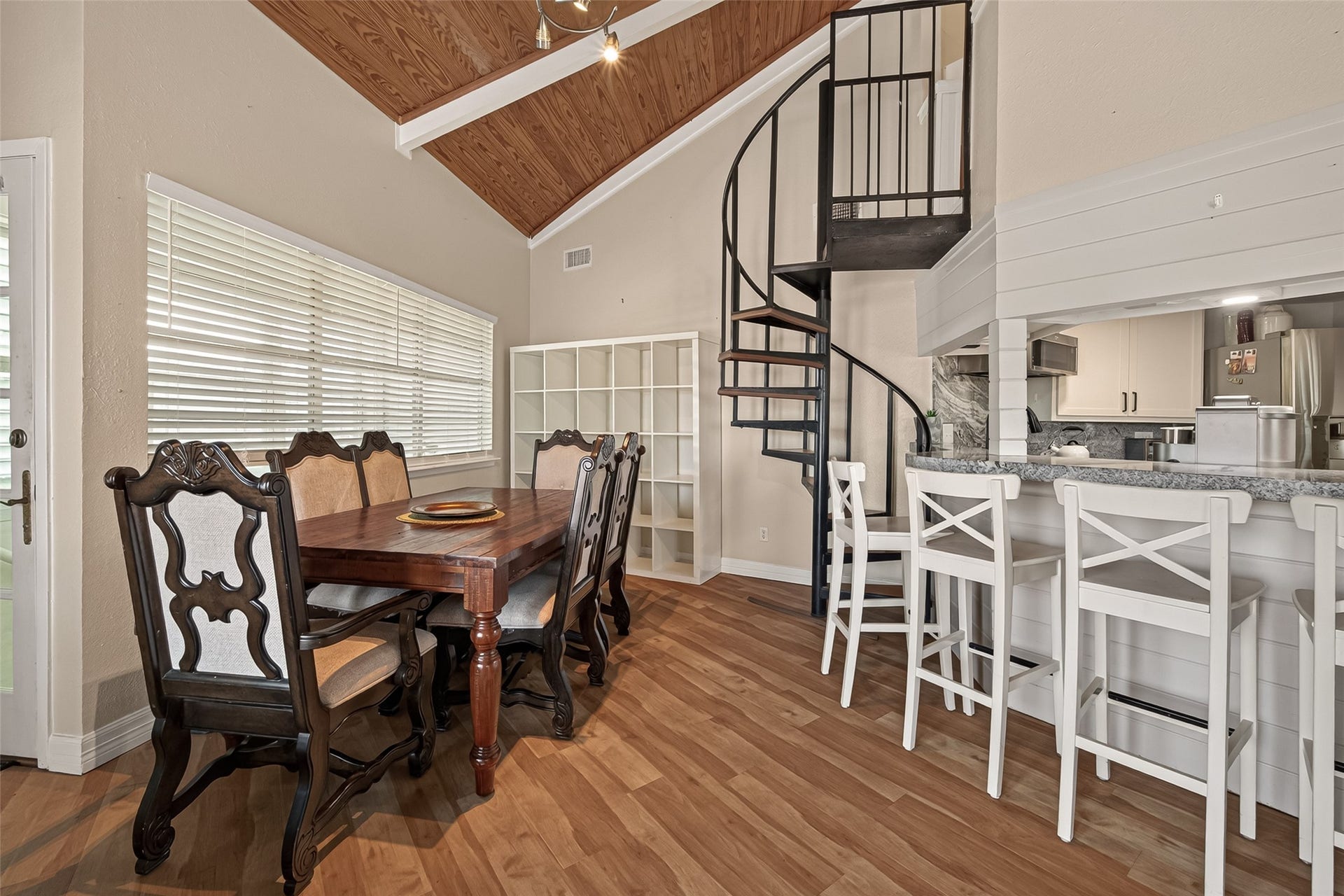 A charming dining setting tucked near a spiral staircase that rises to the private upper-level office.