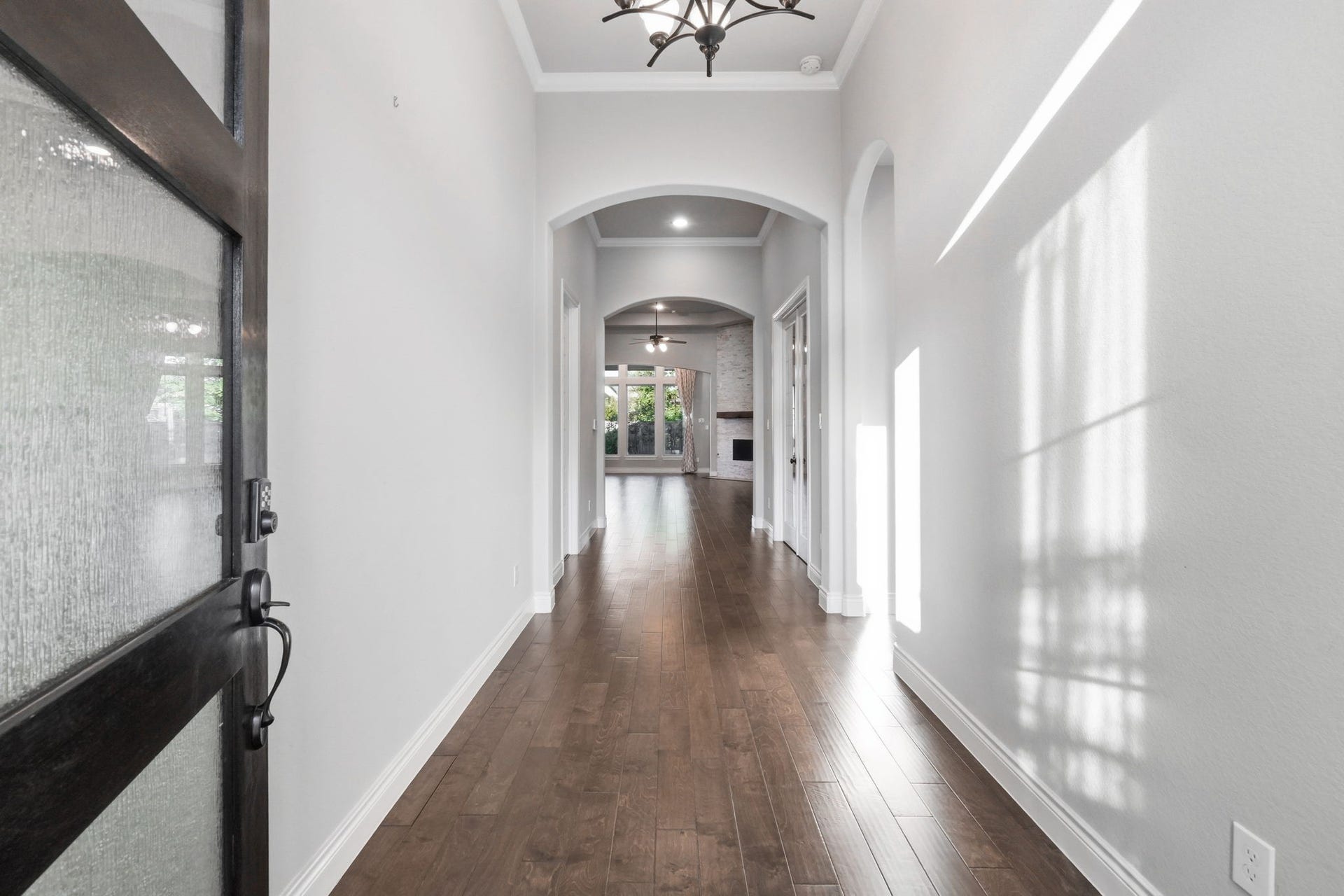 15223 Prairie Dog Town Lane, Cypress, TX 77433 Long hallway with engineered hardwood flooring, tall windows, and a graceful sightline connecting the homes interior spaces.