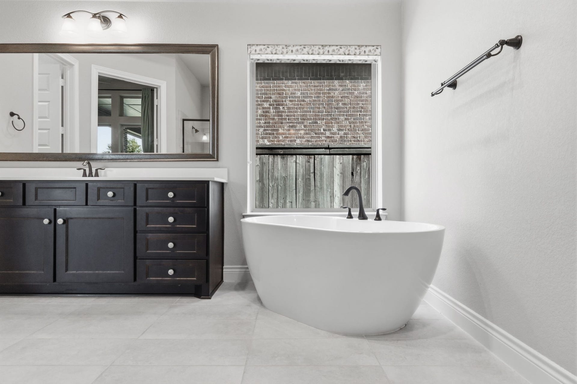 15223 Prairie Dog Town Lane, Cypress, TX 77433 Elegant primary bath highlighting a sculptural soaking tub and sleek dark cabinetry.