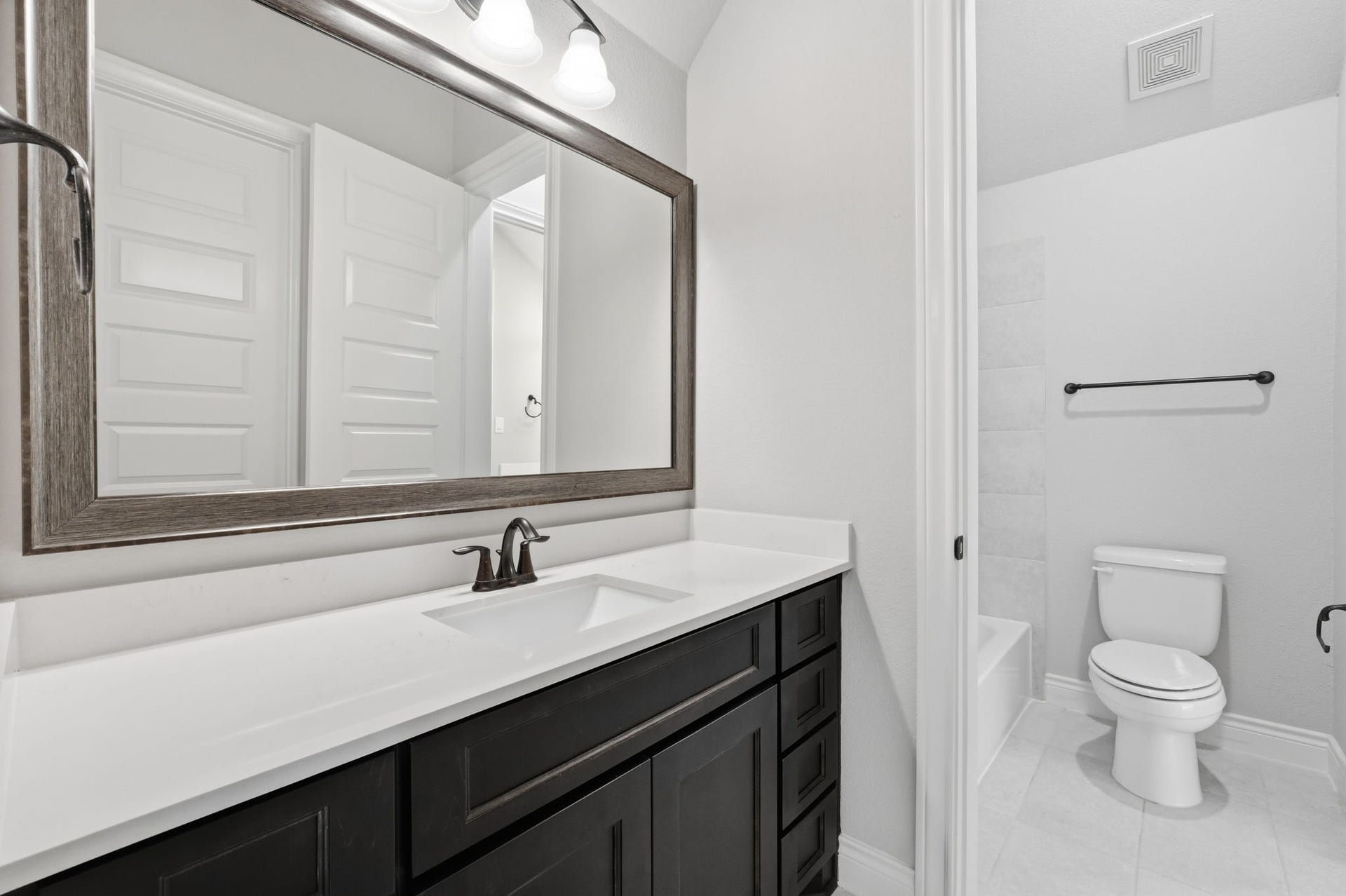15223 Prairie Dog Town Lane, Cypress, TX 77433 Well-appointed secondary bath featuring a sleek vanity, framed mirror, and a soaking tub and shower combination with bright, clean finishes.