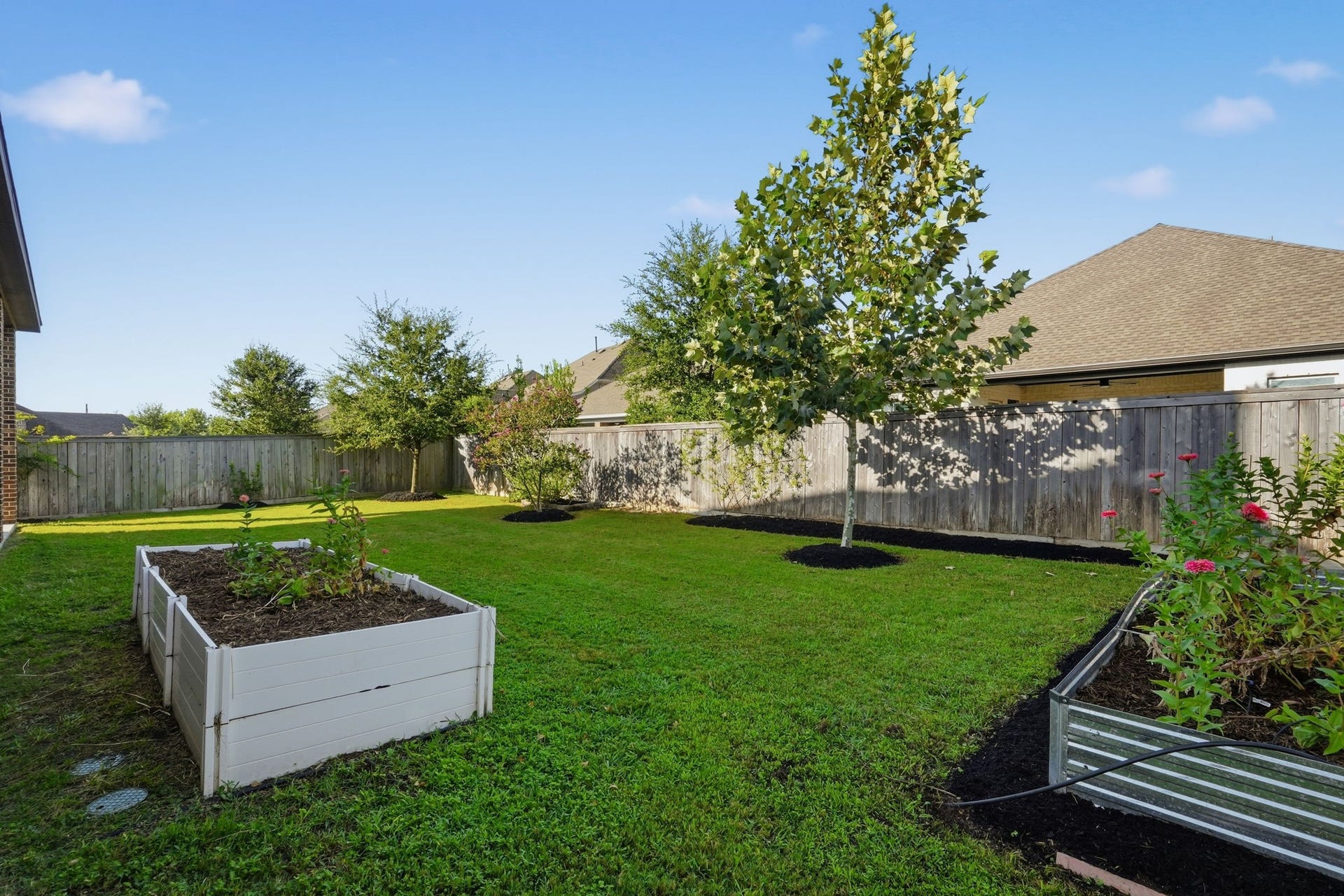 15223 Prairie Dog Town Lane, Cypress, TX 77433 Spacious backyard retreat showcasing a lush lawn, mature trees, raised garden beds, and plenty of room to enjoy the outdoors.