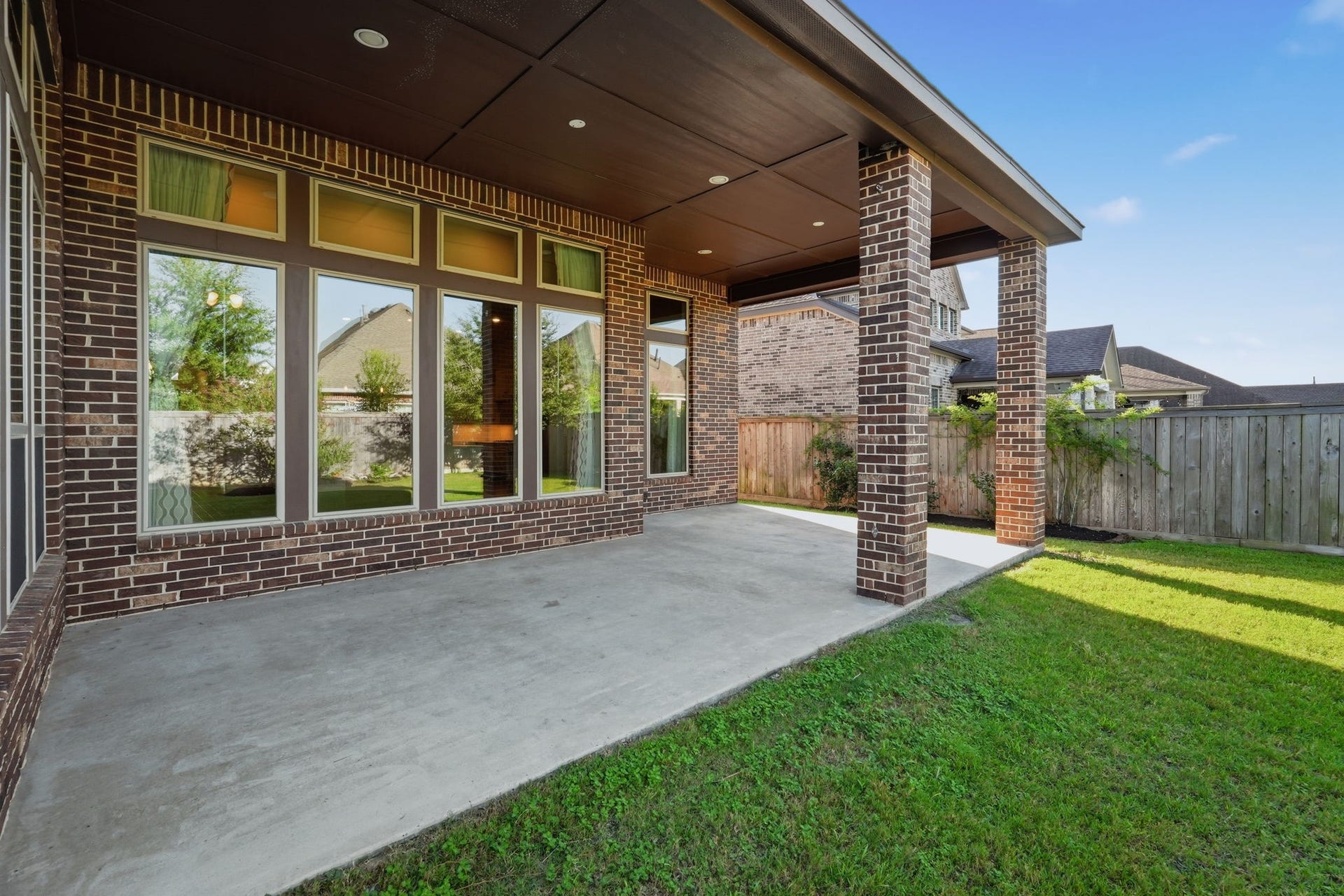 15223 Prairie Dog Town Lane, Cypress, TX 77433 Rear exterior showcasing the expansive covered patio, brick columns, and generous outdoor living area overlooking the lush backyard.