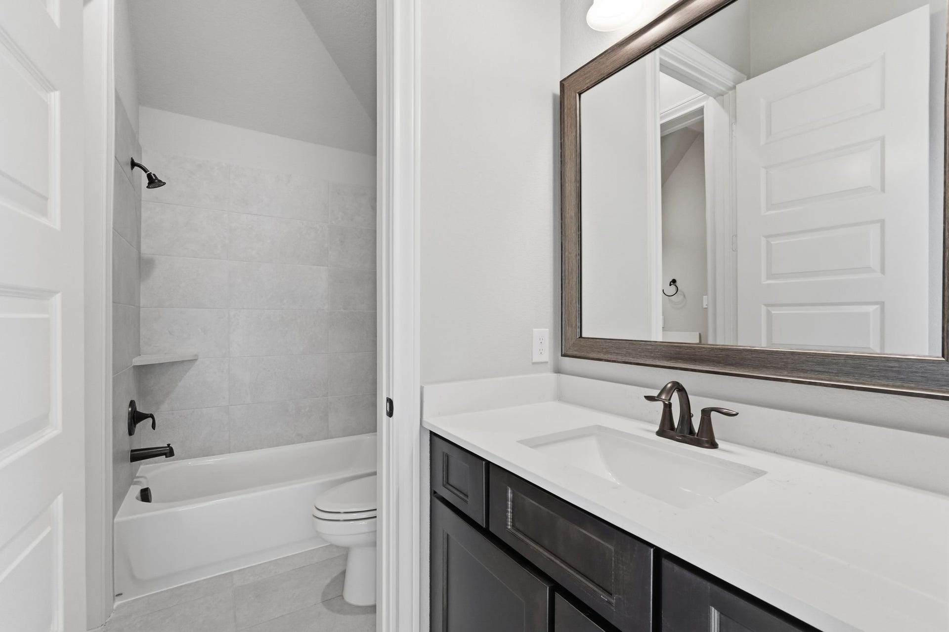 15223 Prairie Dog Town Lane, Cypress, TX 77433 Secondary bath showcasing a generous vanity, framed mirror, and soaking tub and shower combination, complemented by crisp, timeless finishes.
