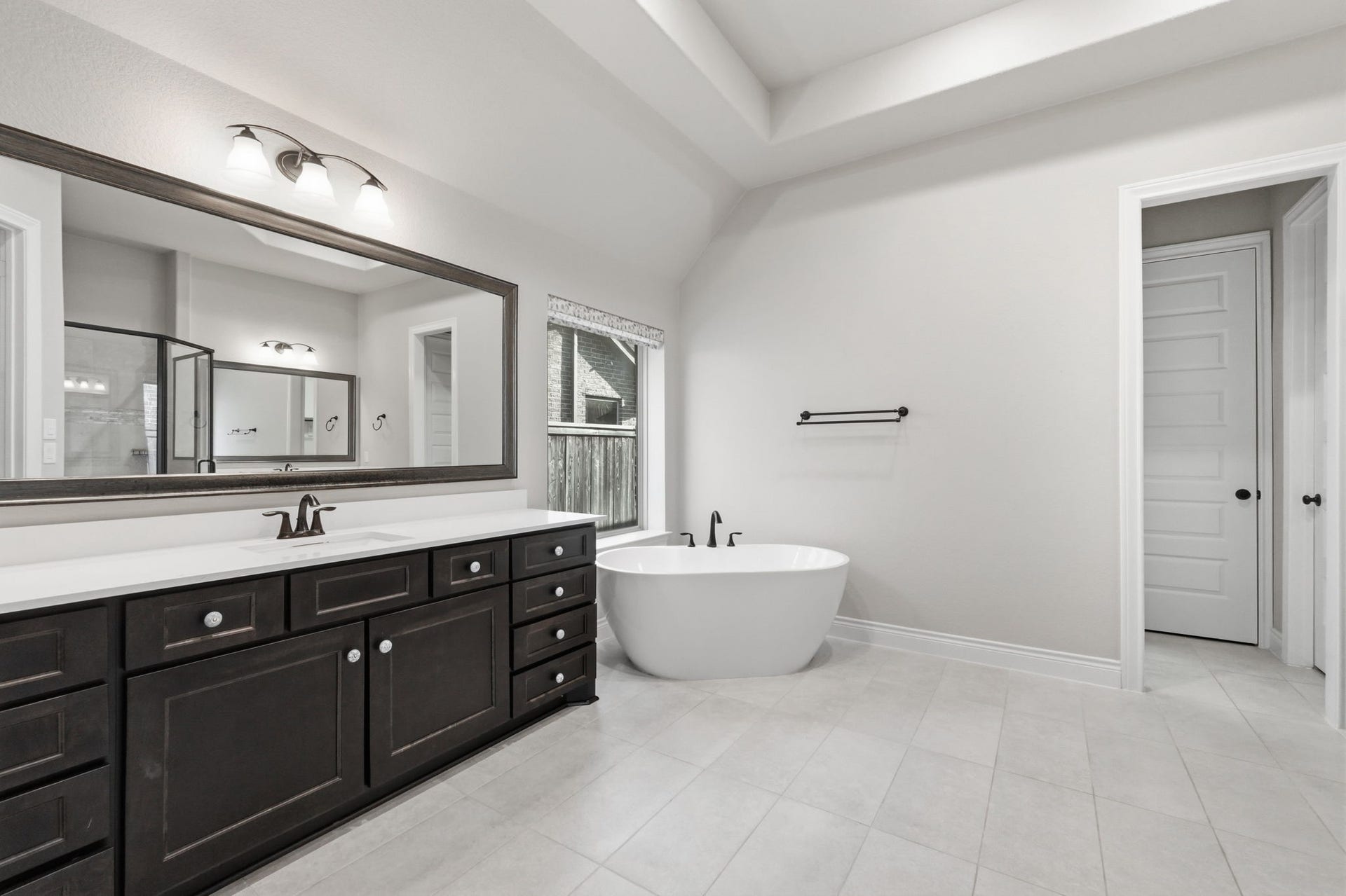 15223 Prairie Dog Town Lane, Cypress, TX 77433 Primary bathroom with separate dual vanities, a soaking tub, and a walk-in shower complemented by a generous mirror.