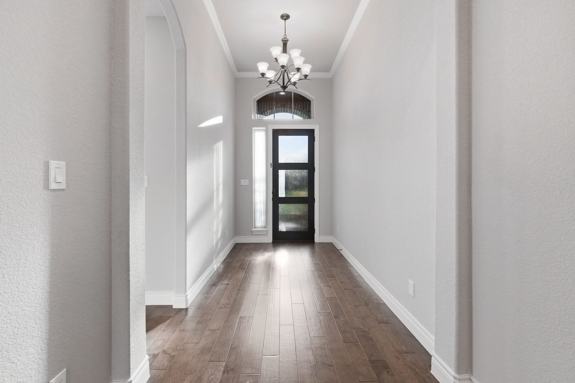 15223 Prairie Dog Town Lane, Cypress, TX 77433 Elegant hallway with engineered hardwood floors, crisp trim details, and a striking view toward the front entry.