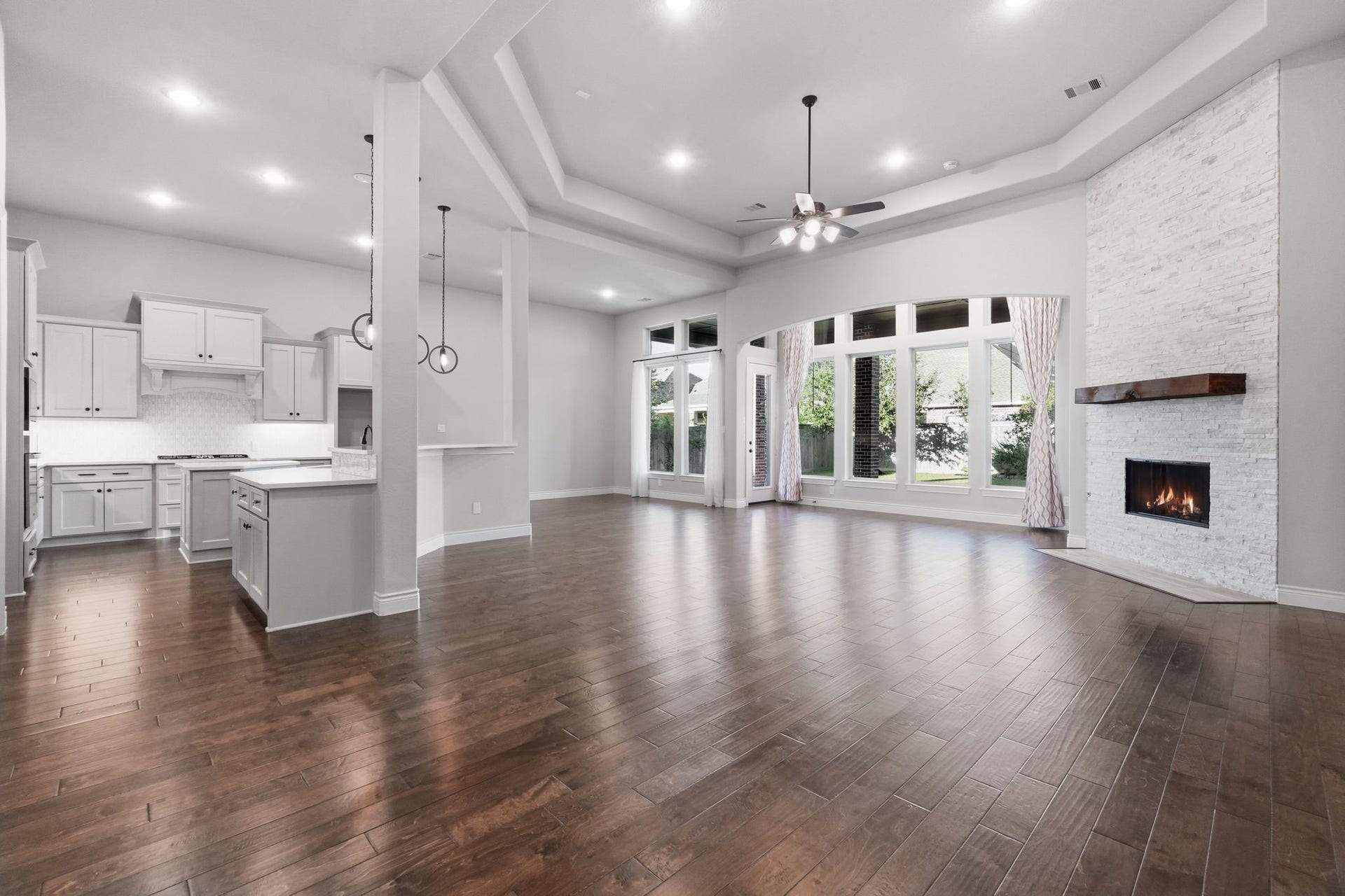 15223 Prairie Dog Town Lane, Cypress, TX 77433 Open-concept great room showcasing a dramatic coffered ceiling, expansive windows, engineered hardwood floors, and seamless flow into the kitchen.
